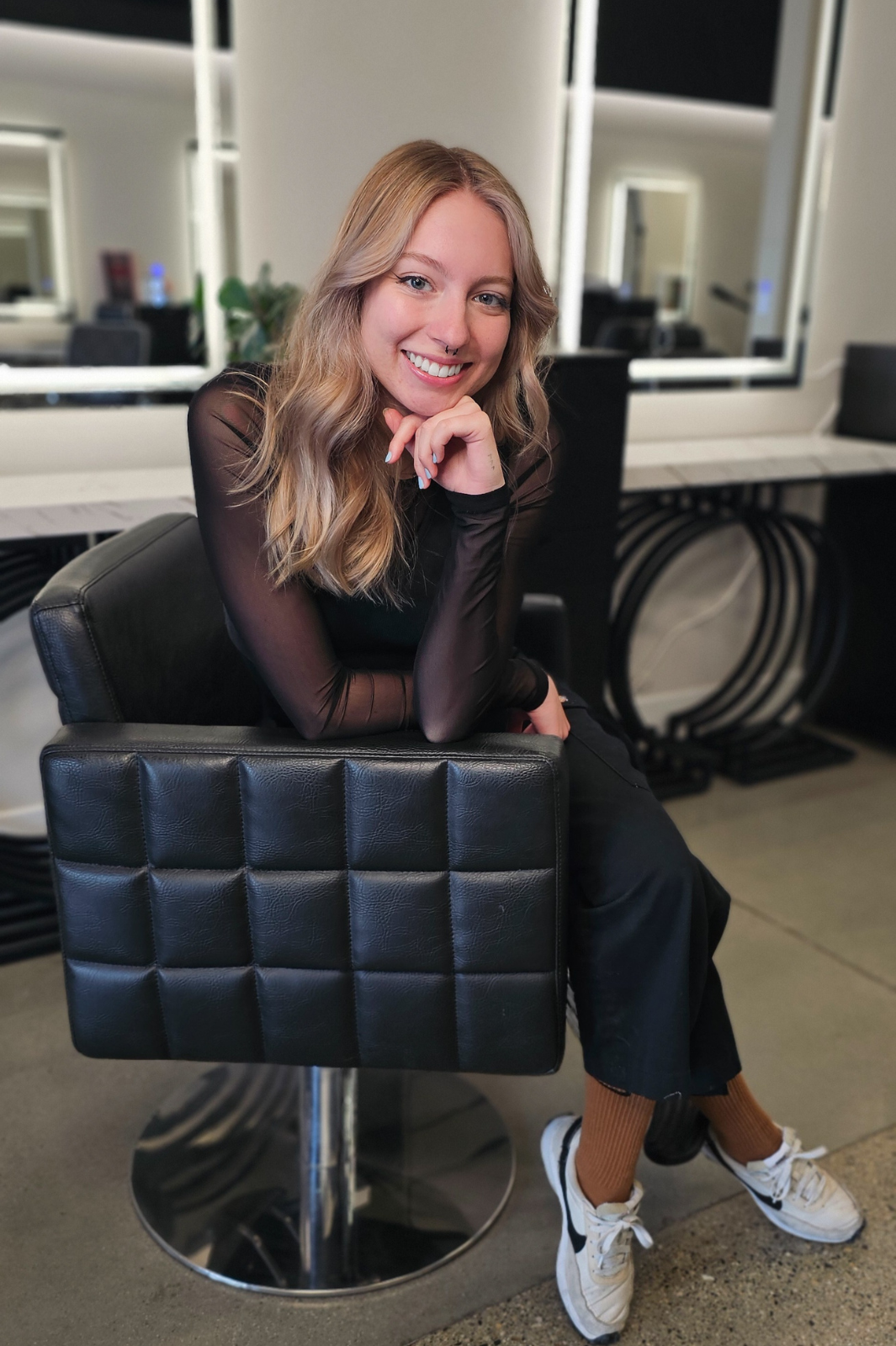 A woman in a black shirt is sitting in a black chair.