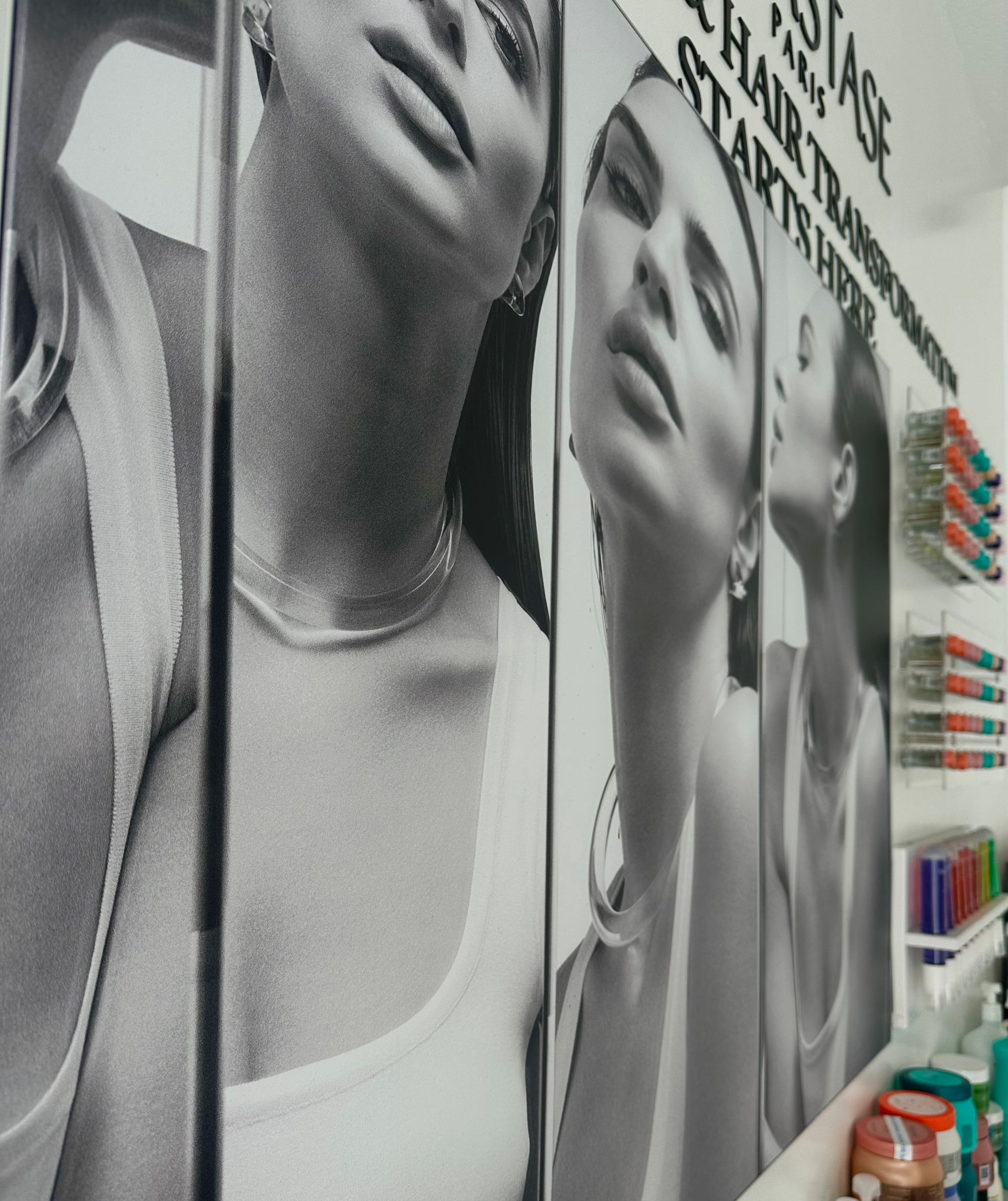 Black and white wall advertisement featuring a woman's face and neck in a beauty salon.