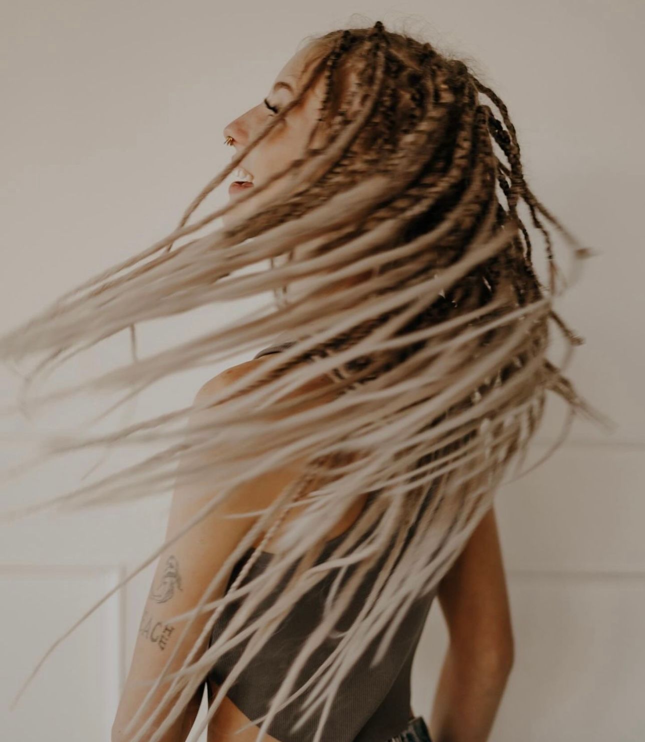 A woman with dreadlocks is standing with her hair blowing in the wind.