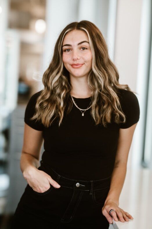 A woman wearing a black shirt and a necklace is smiling for the camera.