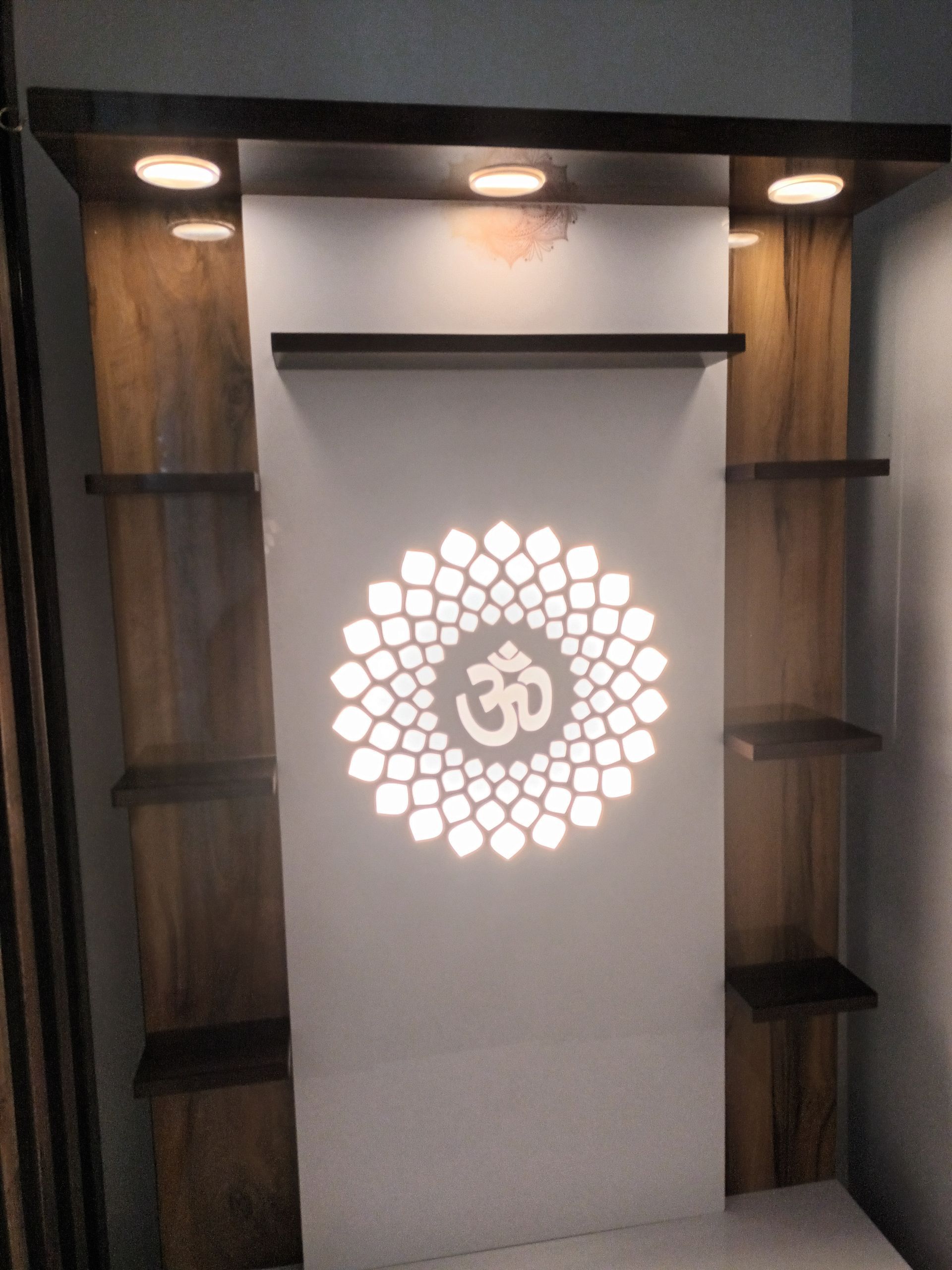 Wooden wall unit with a lit Om symbol, shelves, and recessed lighting. — Ryphen Electrical in Highton, VIC