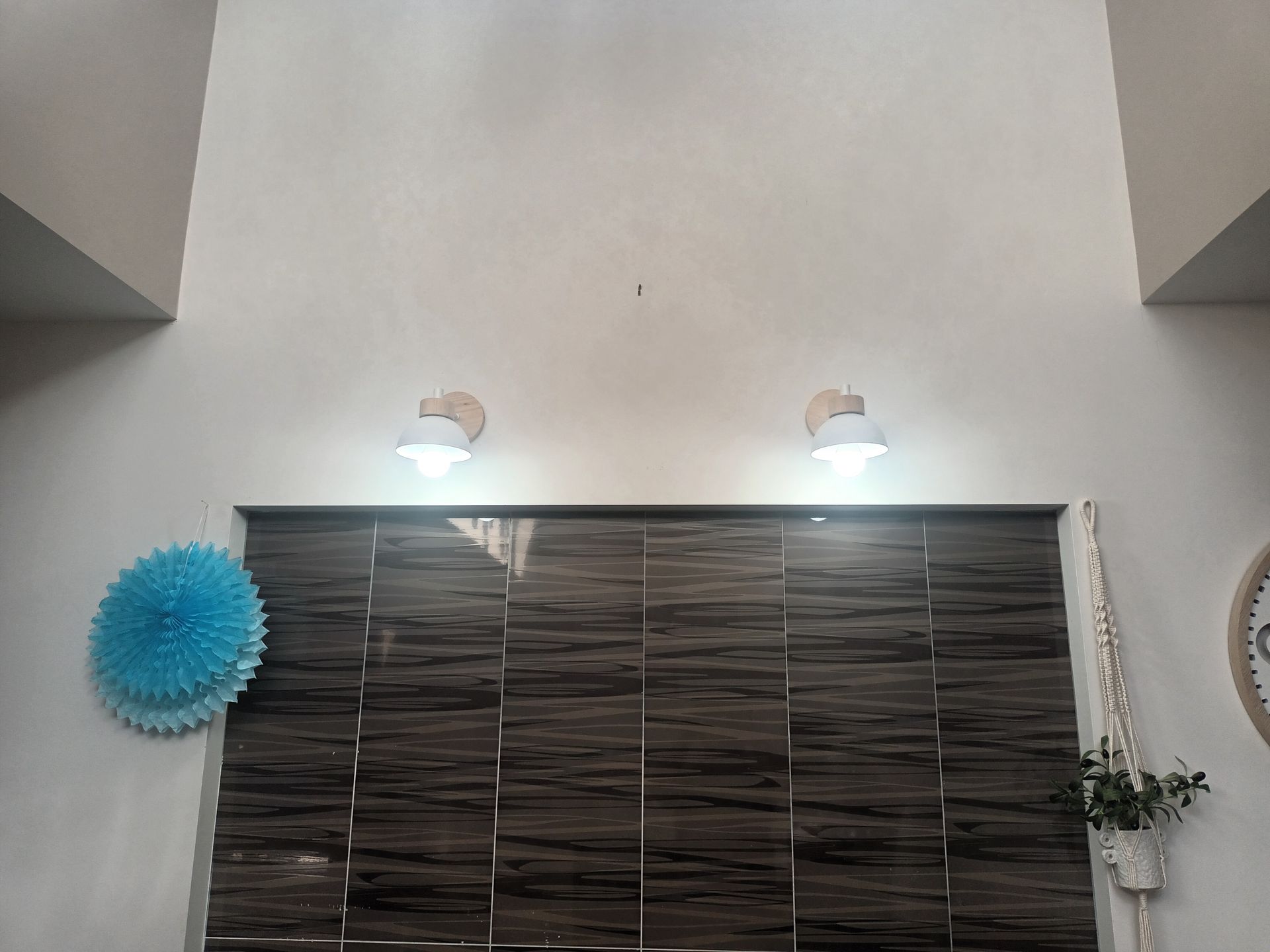 Brown textured wall with two sconce lights above and a blue paper decoration on the left. — Ryphen Electrical in Highton, VIC
