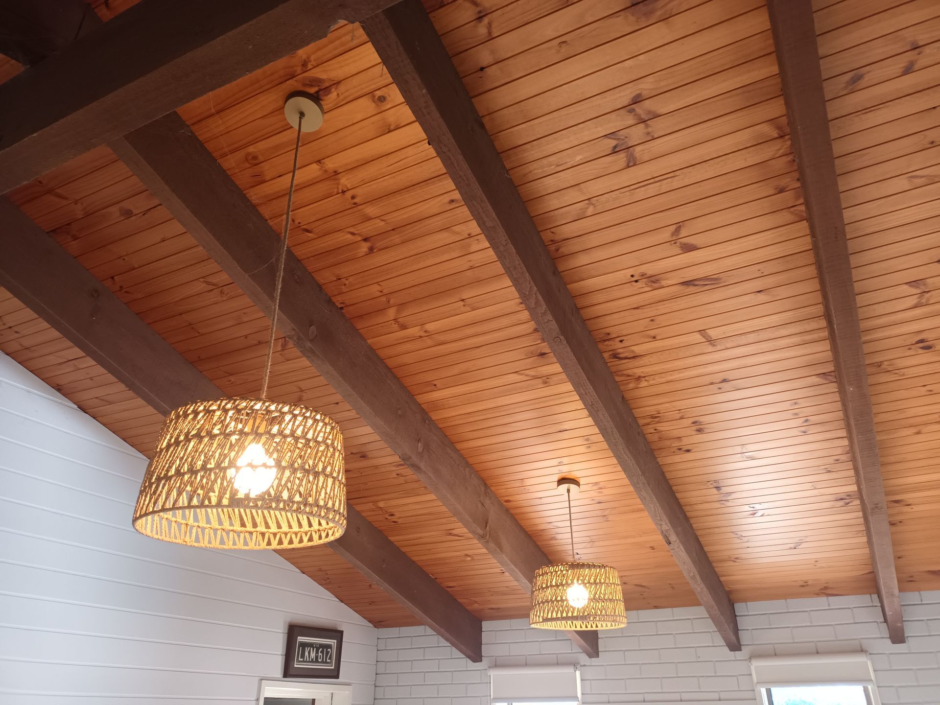 Wooden ceiling with brown beams, two woven pendant lights, and white brick walls. — Ryphen Electrical in Highton, VIC