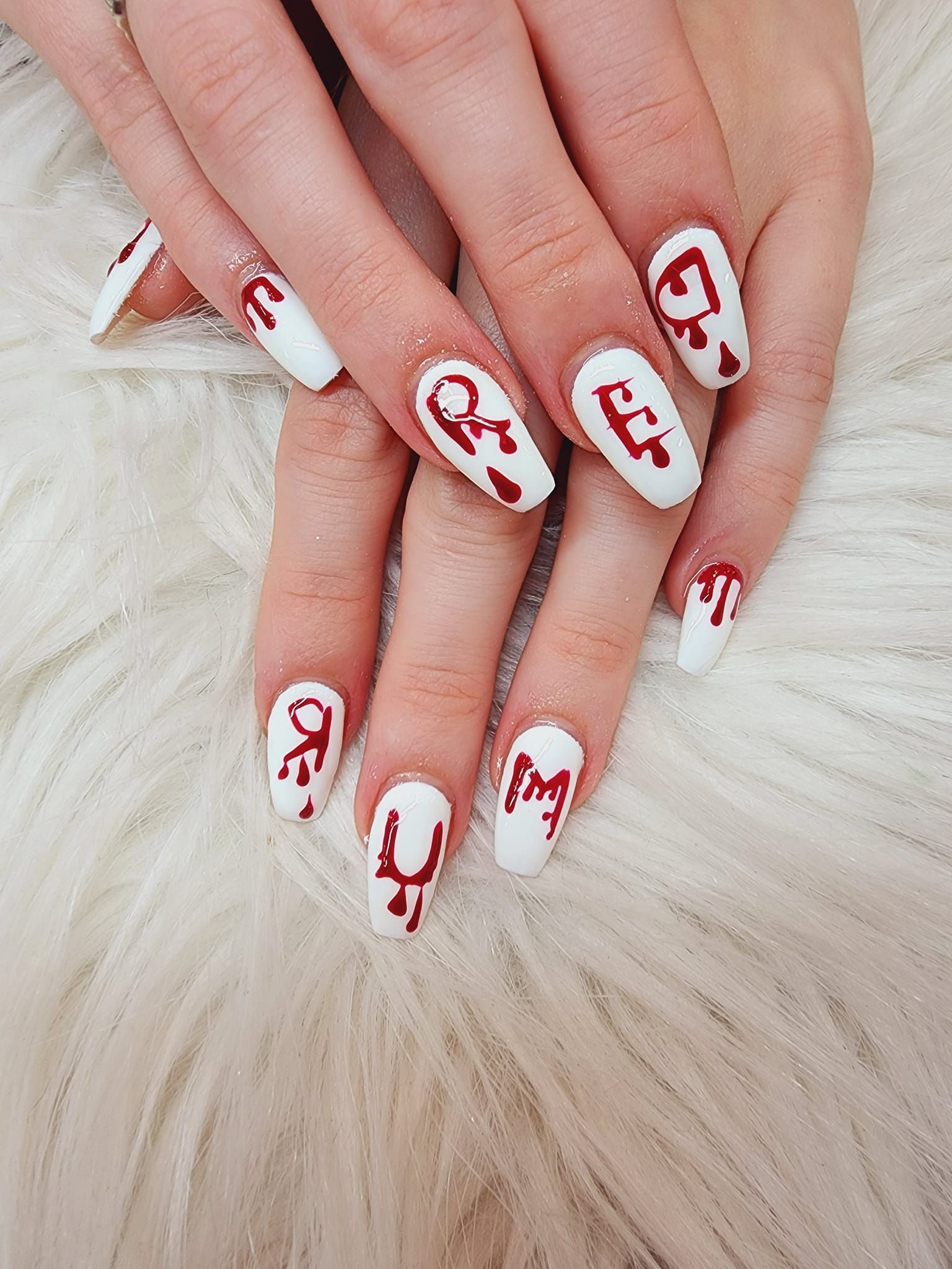 A close up of a woman 's nails with red and white designs on them.