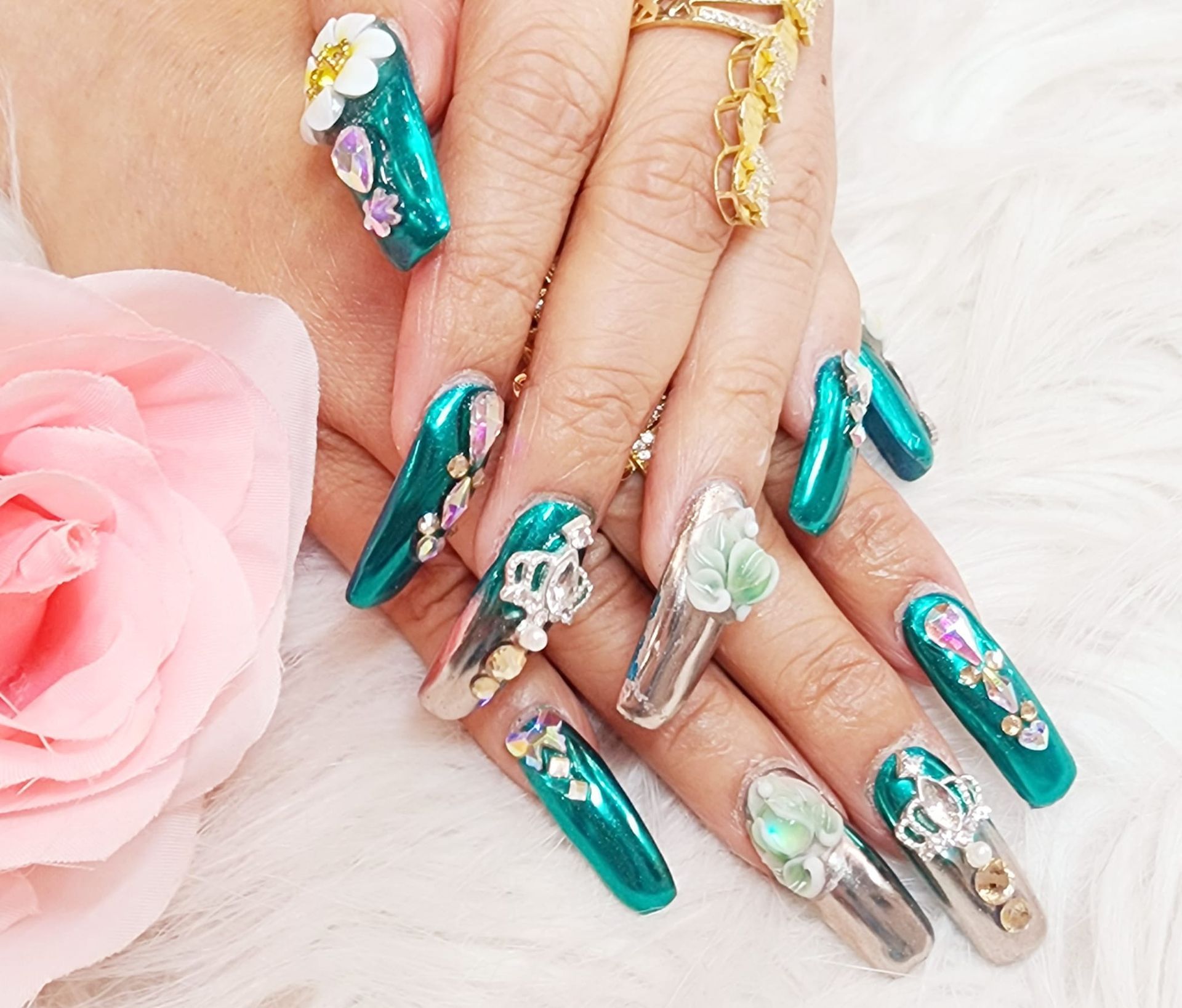 A close-up of a woman's nails with a pink rose in the background.