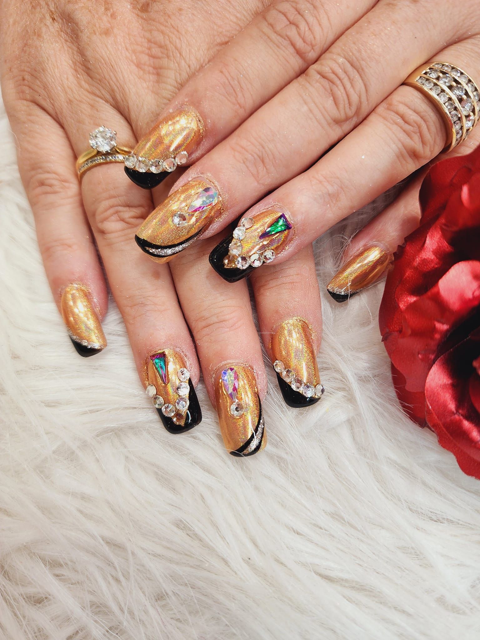 A close-up of a woman's hands with gold nails and rings.