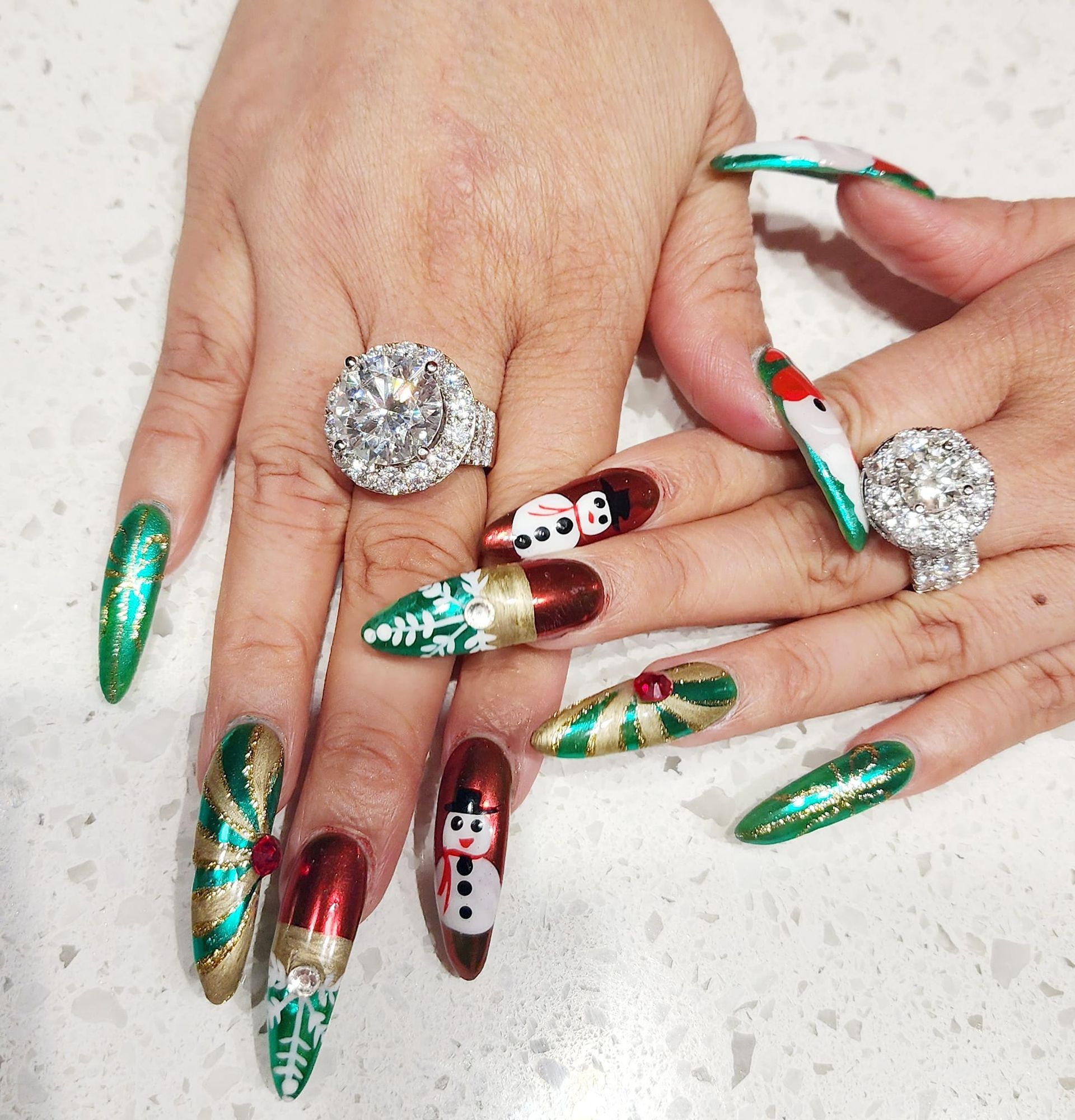 A woman 's hands with christmas nails and rings on them.