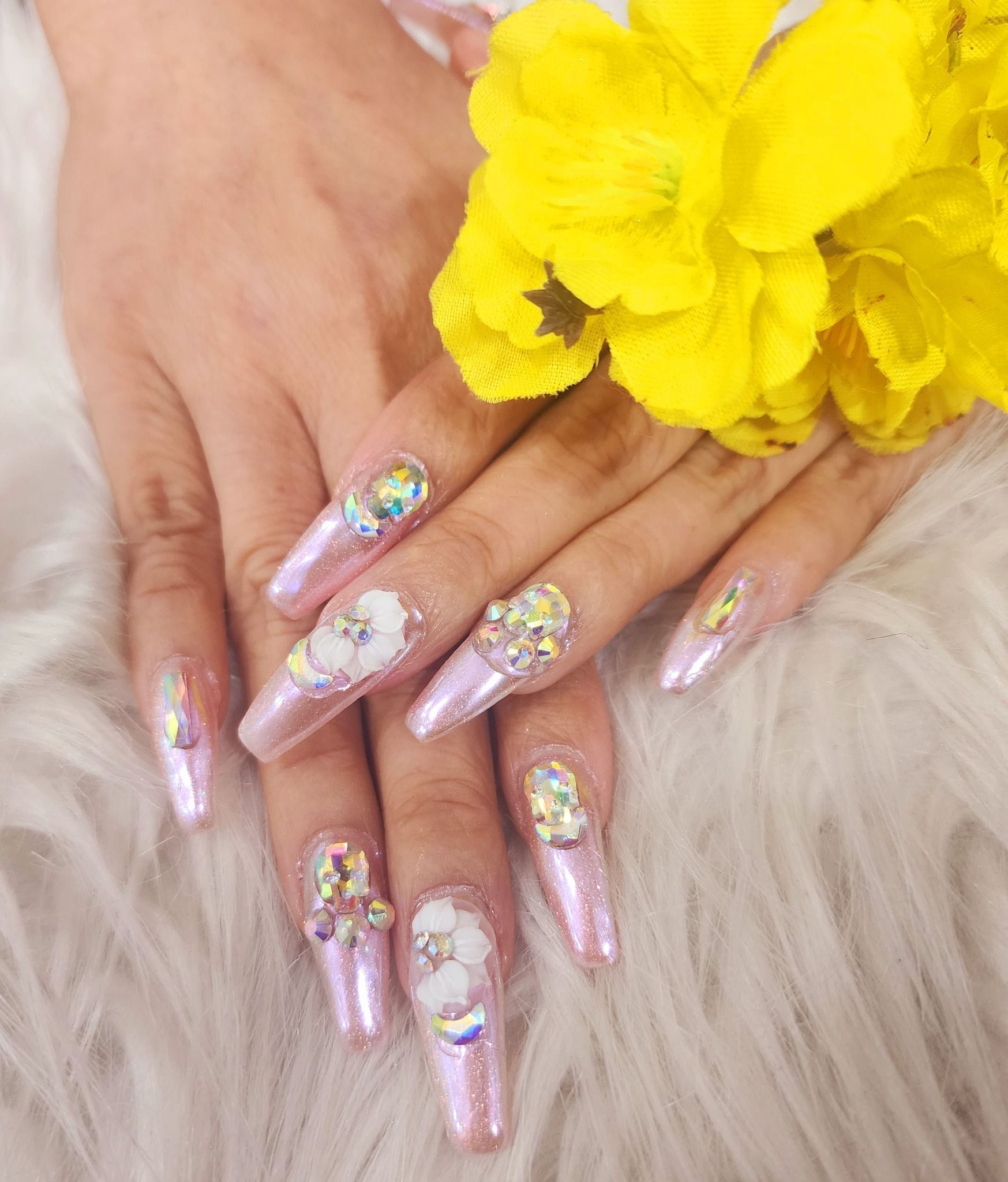 A close up of a woman 's nails with a yellow flower in the background.