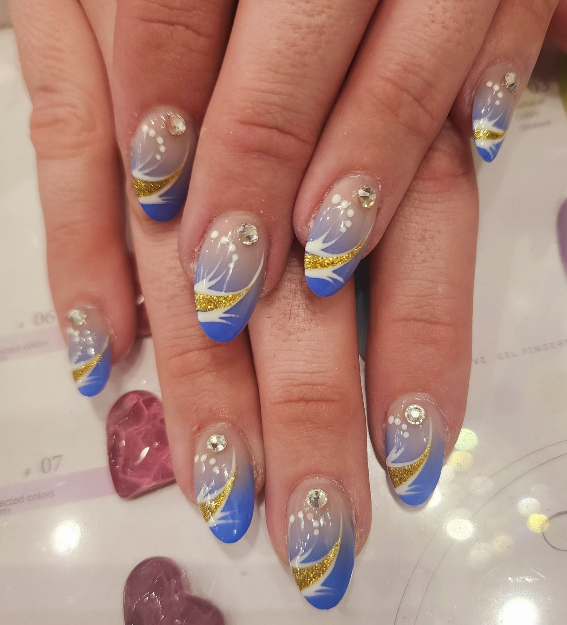 A close up of a woman 's nails with blue and gold designs.