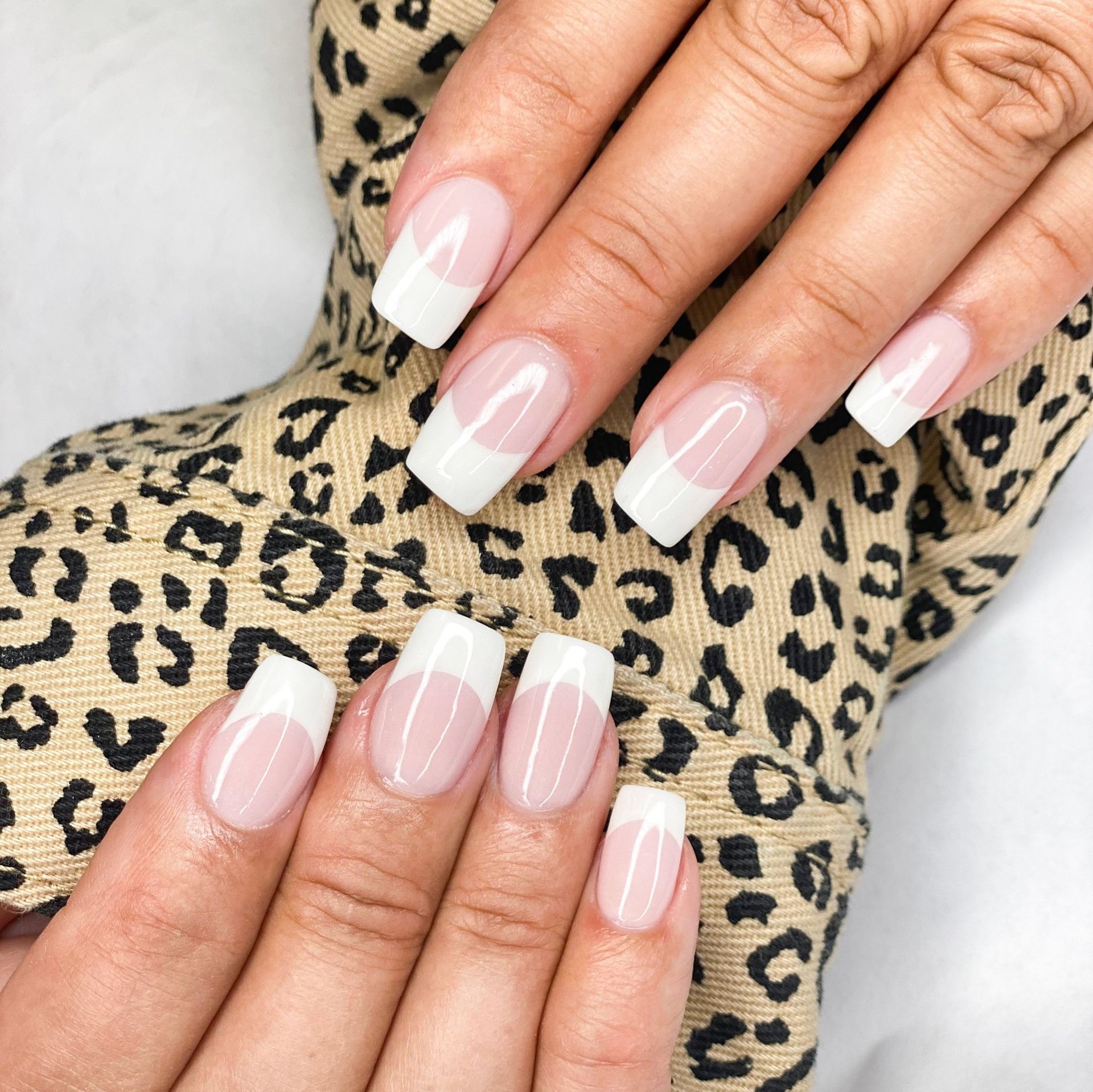 A close up of a woman 's nails on a leopard print scarf.