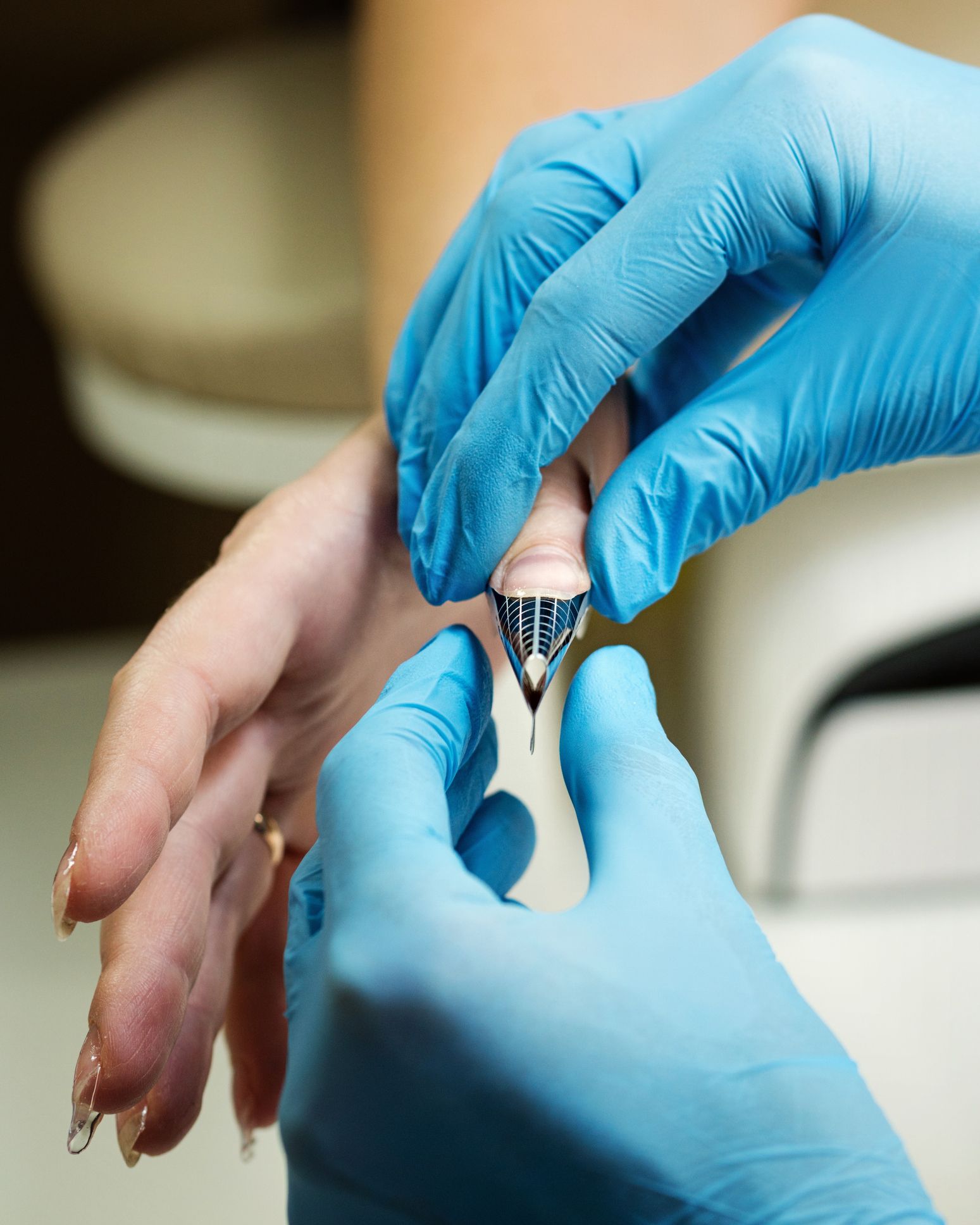 A person wearing blue gloves is putting a ring on a woman's finger.