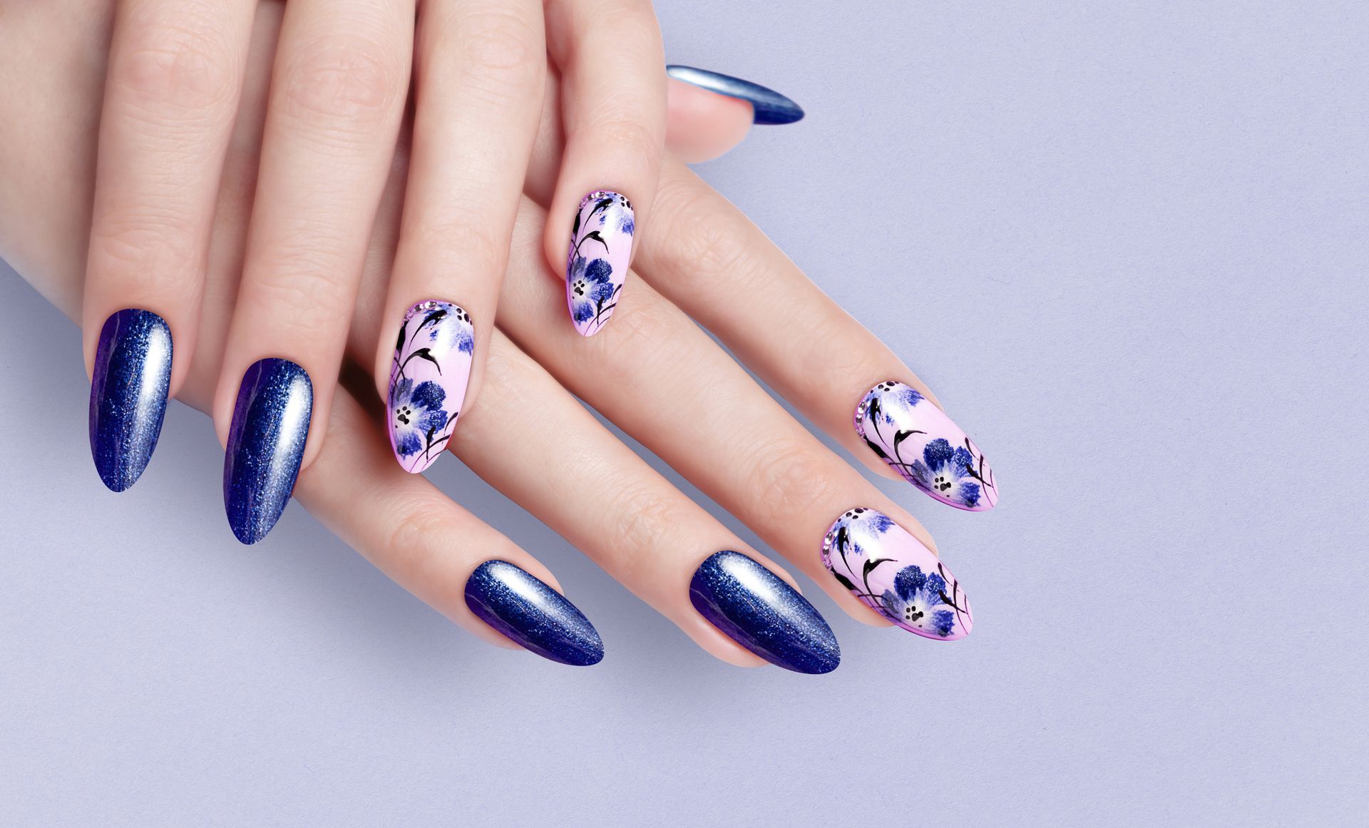A close up of a woman's hands with blue nails and a floral design.