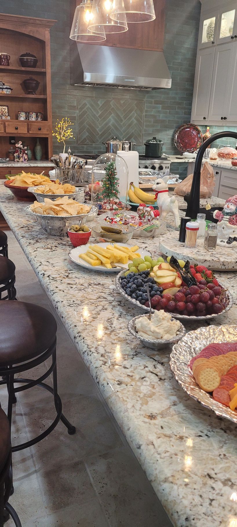 Buffet spread on a kitchen island with fruit, cheese, and appetizers in a home kitchen