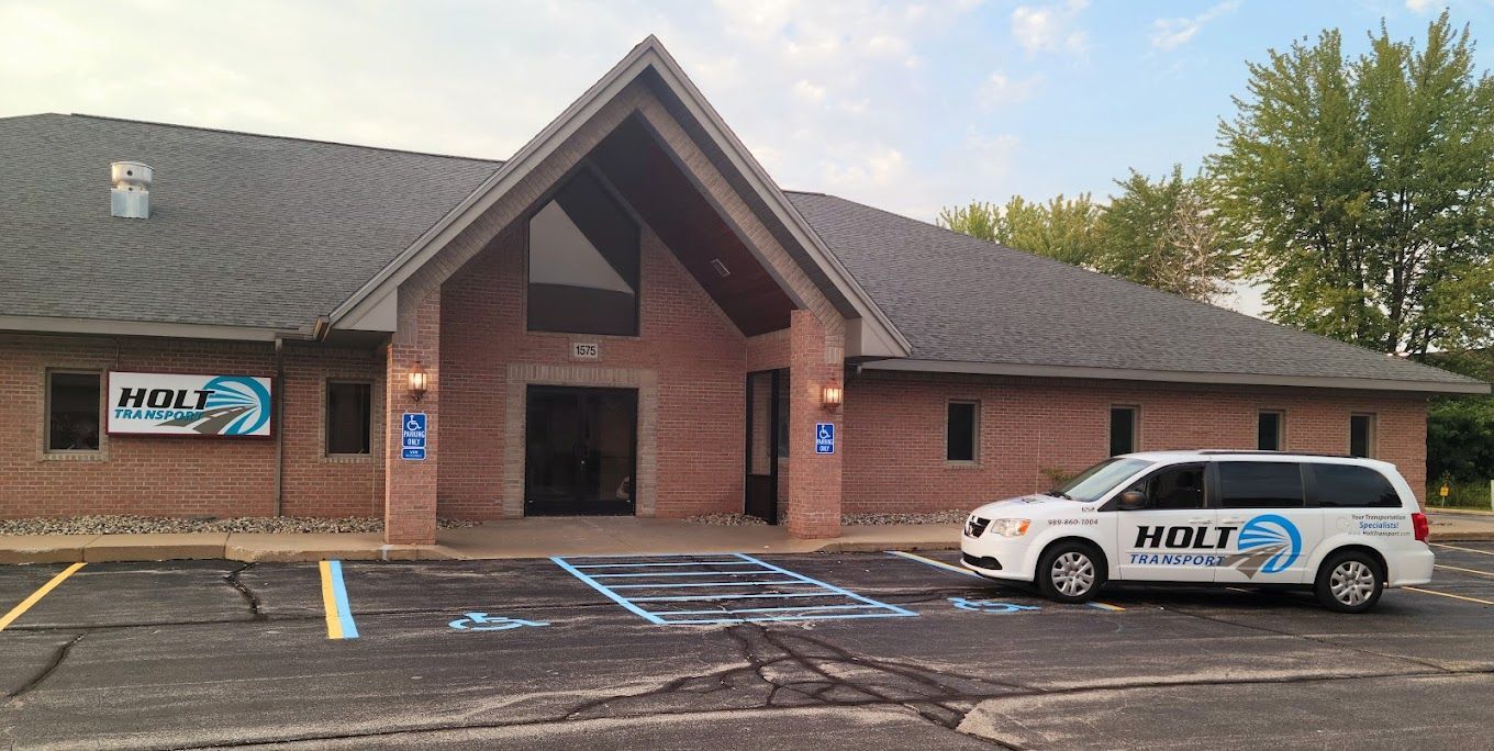 A white van is parked in front of a brick building