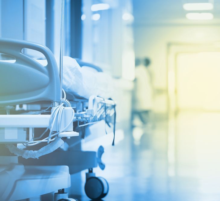 A hospital hallway with a row of hospital beds and a doctor in the background.