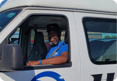 A man in a blue shirt is sitting in the driver 's seat of a white van.