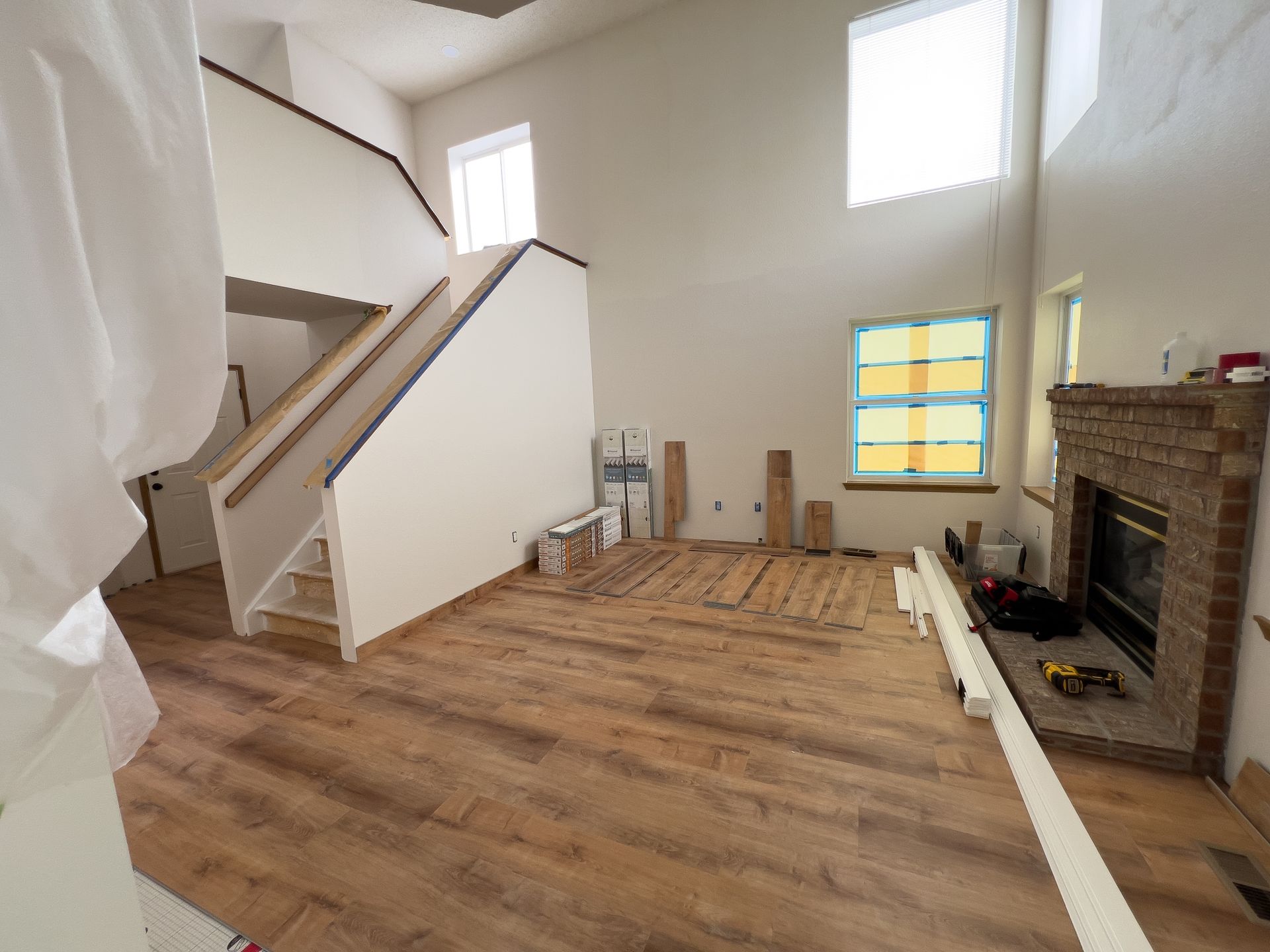 A living room under renovation with new wood-look flooring.