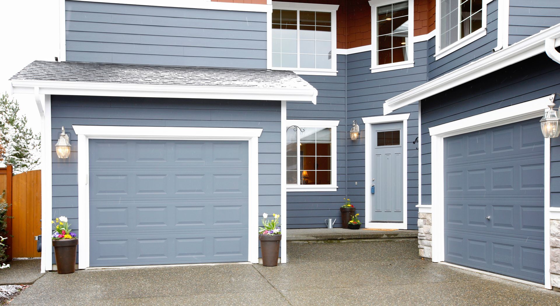 A two-story blue house exterior with two garage doors.