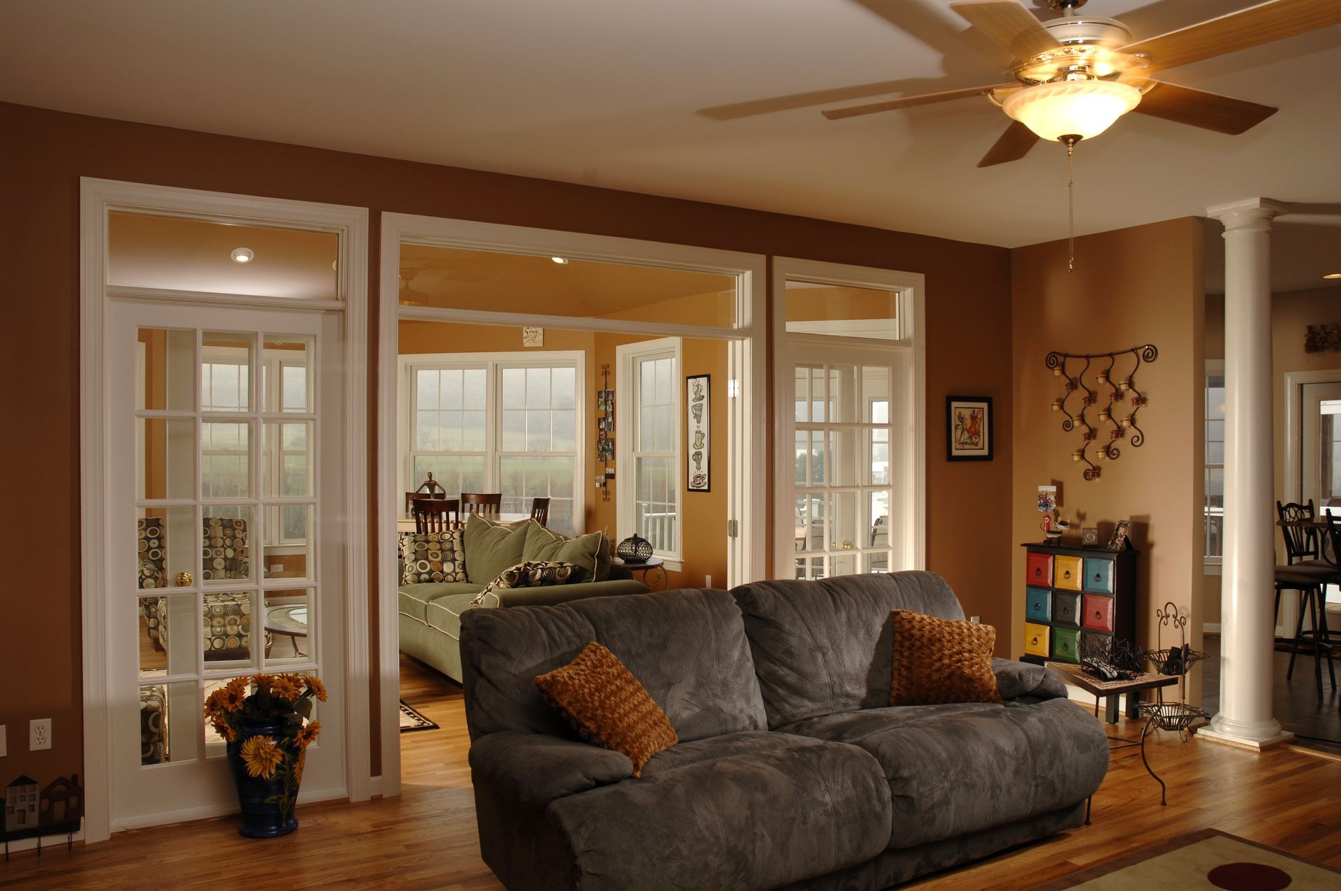 A living room with a dark gray sofa, wood floors, a ceiling fan.
