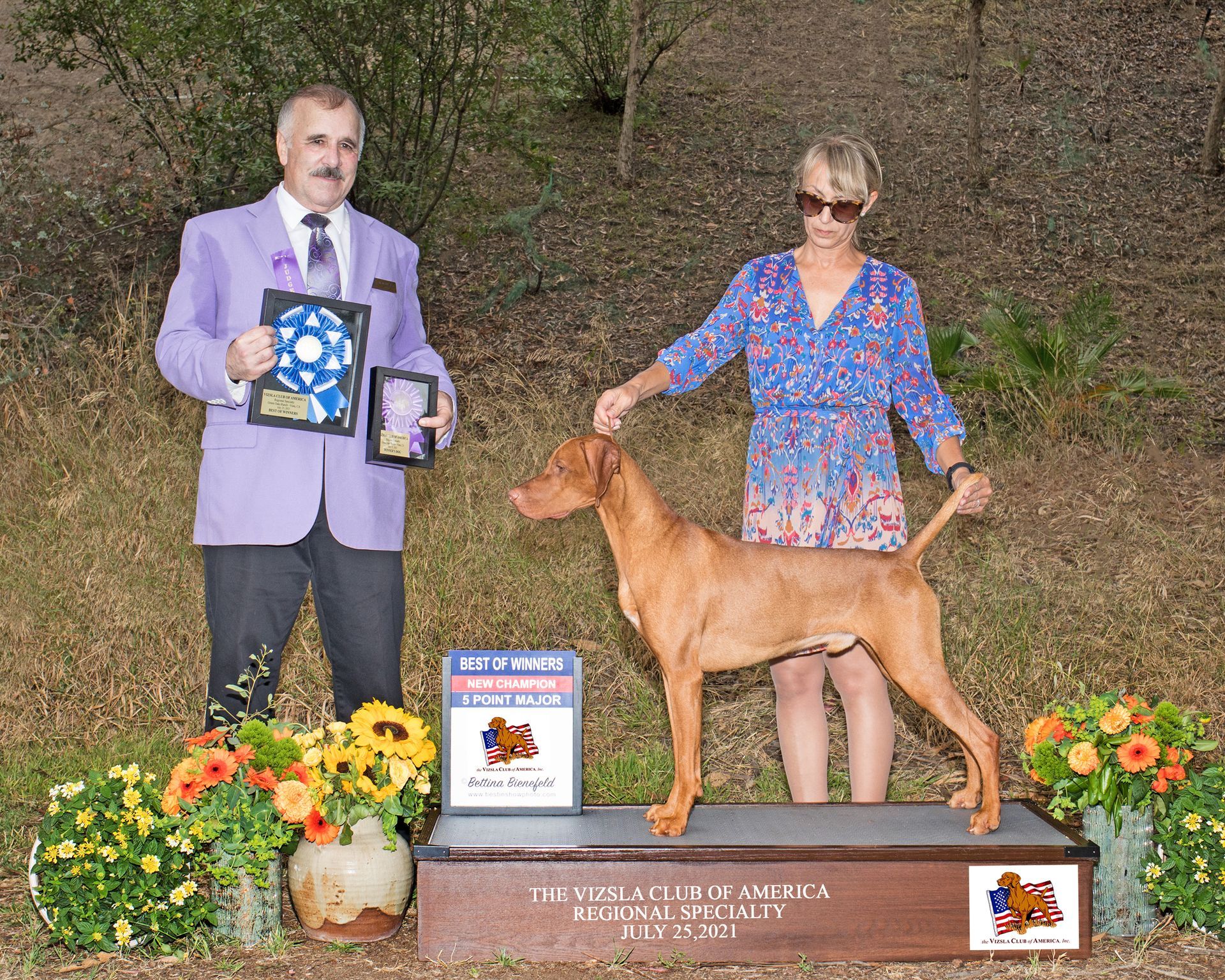 A man and woman standing next to a dog on a podium