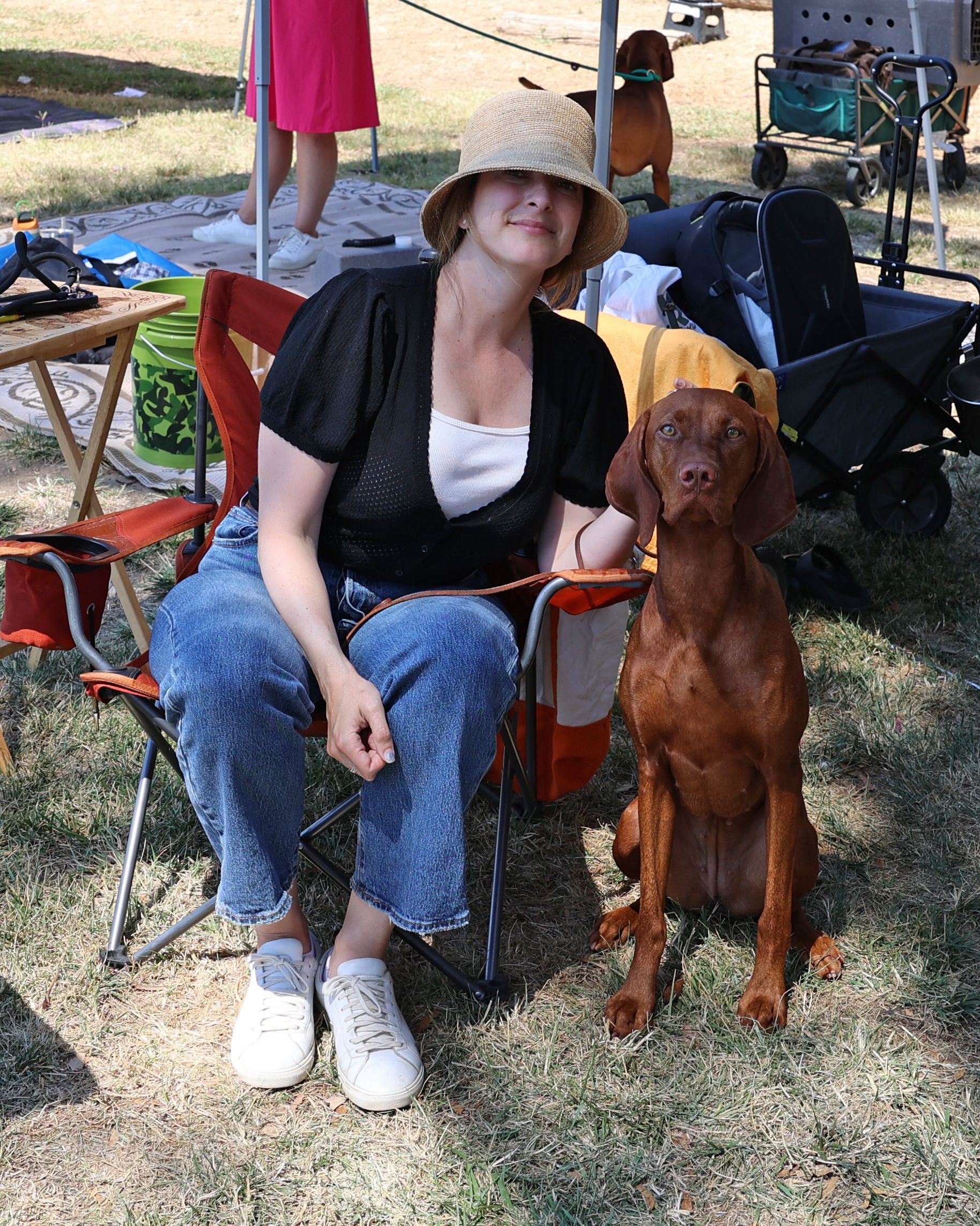 A woman is sitting in a chair next to a brown dog