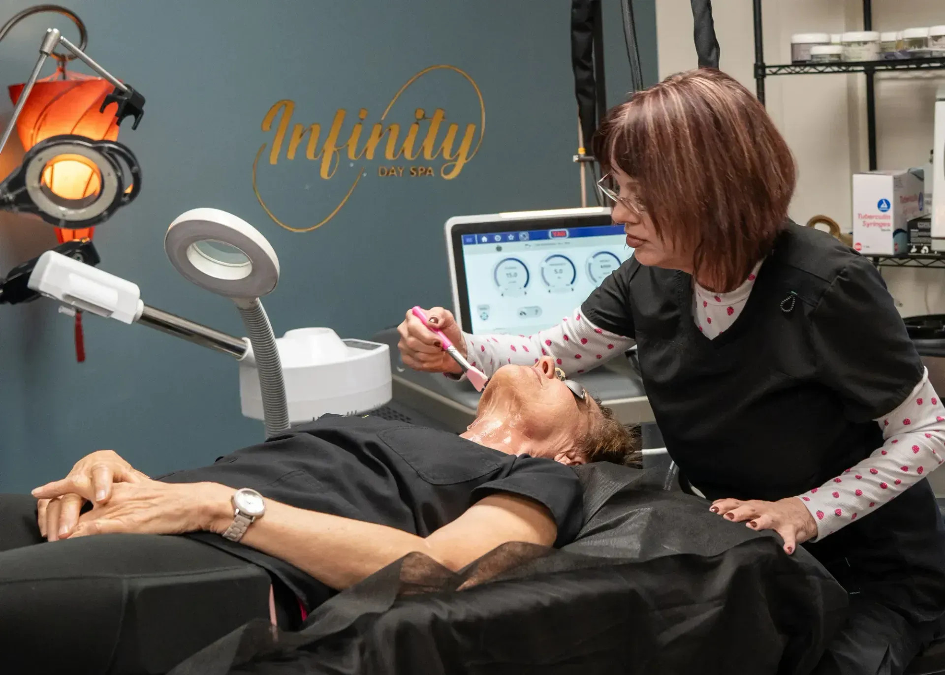 Esthetician examining a client's face, using tools in a skincare treatment room.