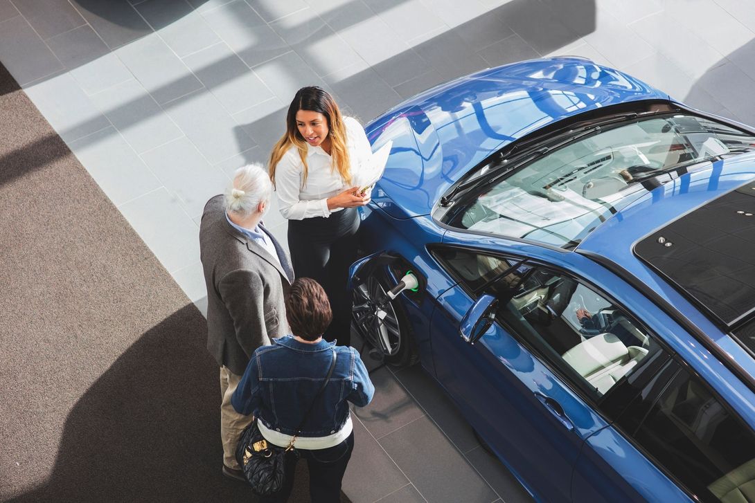 Un gruppo di persone guarda un'auto blu in uno showroom.