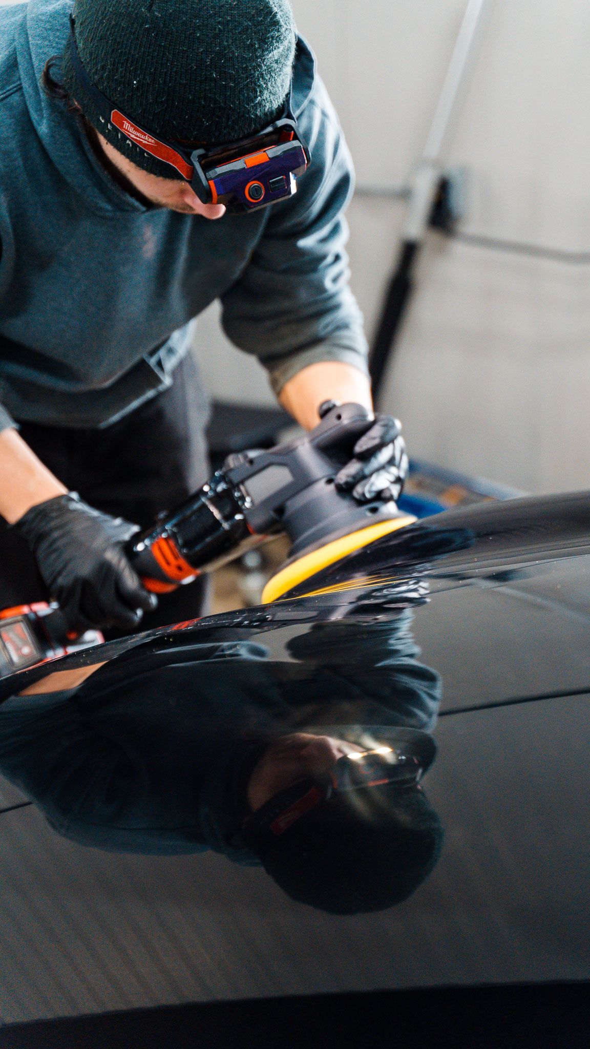 Green BMW coupe with a rear wing, parked in a garage.