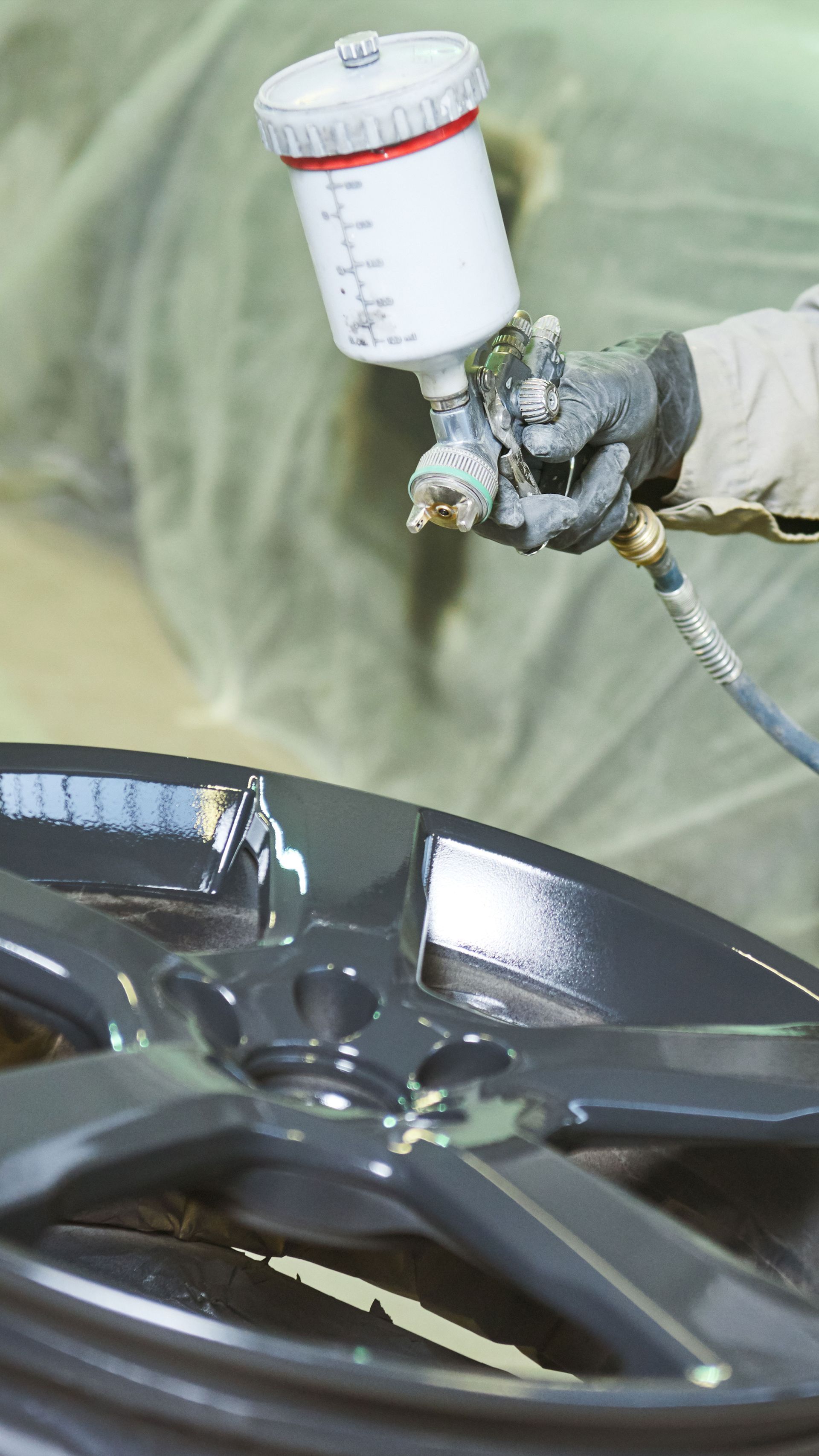 Silver BMW coupe parked on a rooftop in front of a gray fence and bare trees under a cloudy sky.