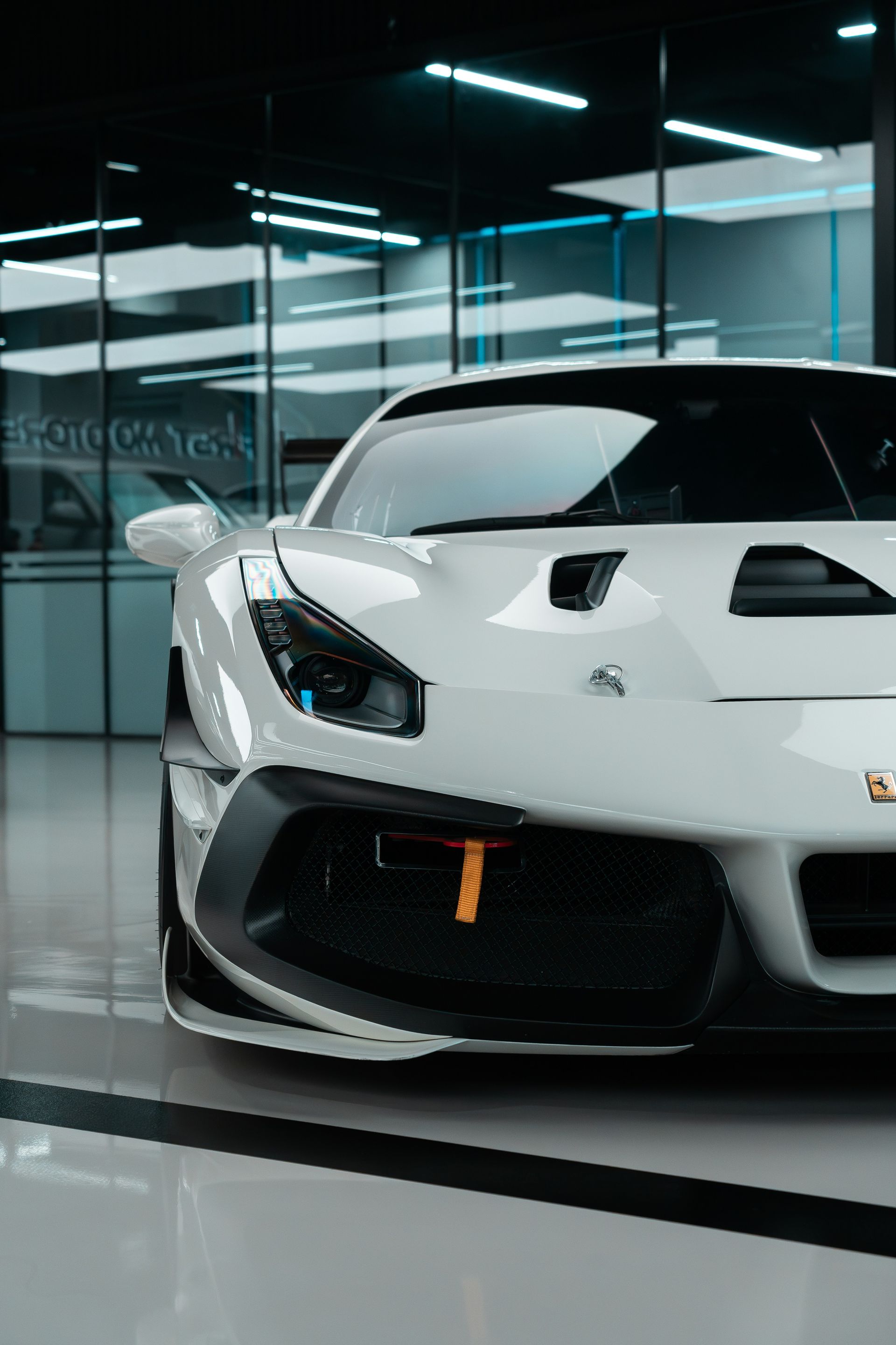 A person is using a blue squeegee to remove plastic from the hood of a car