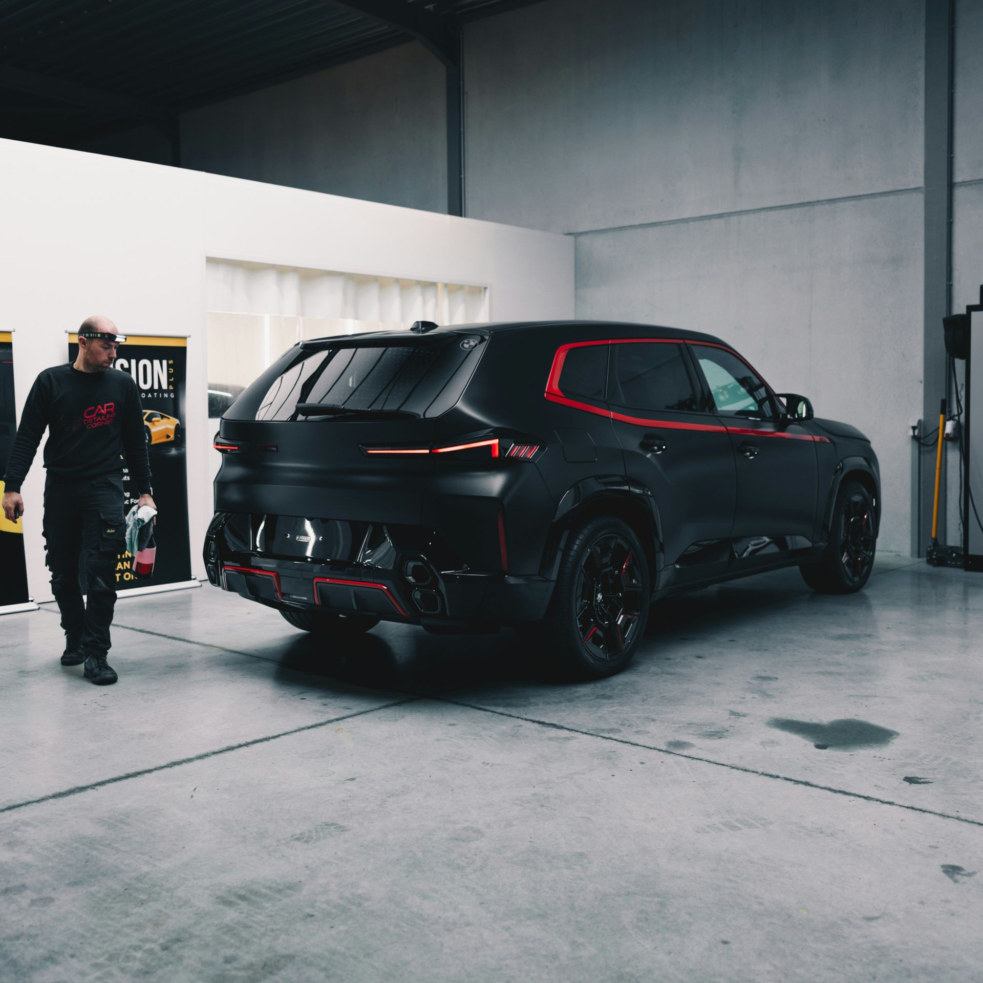 Black BMW SUV with red accents, in a garage; a person walks by.