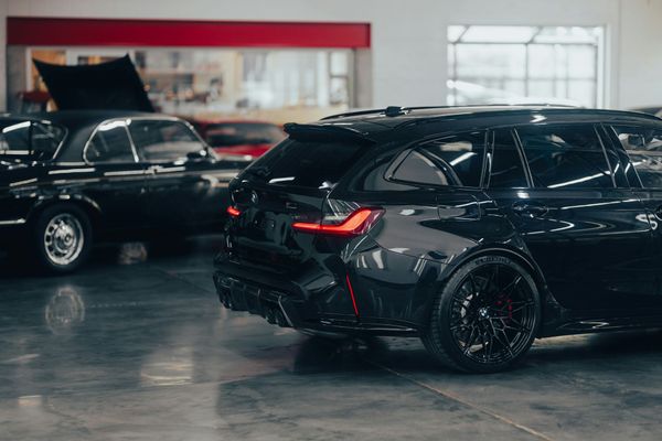 A person is cleaning a blue car with an orange towel