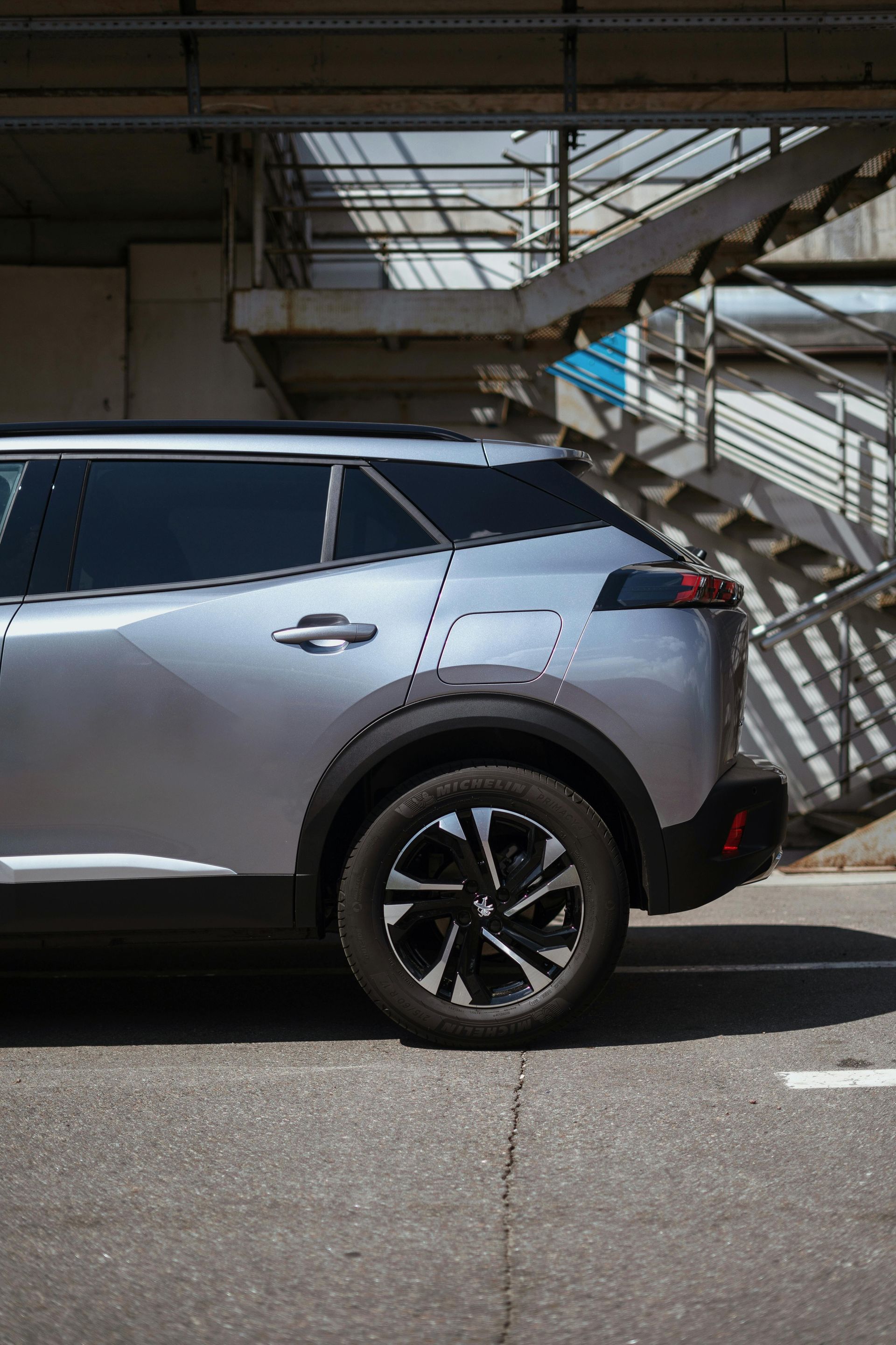 Silver SUV parked near a concrete wall with a metal staircase.