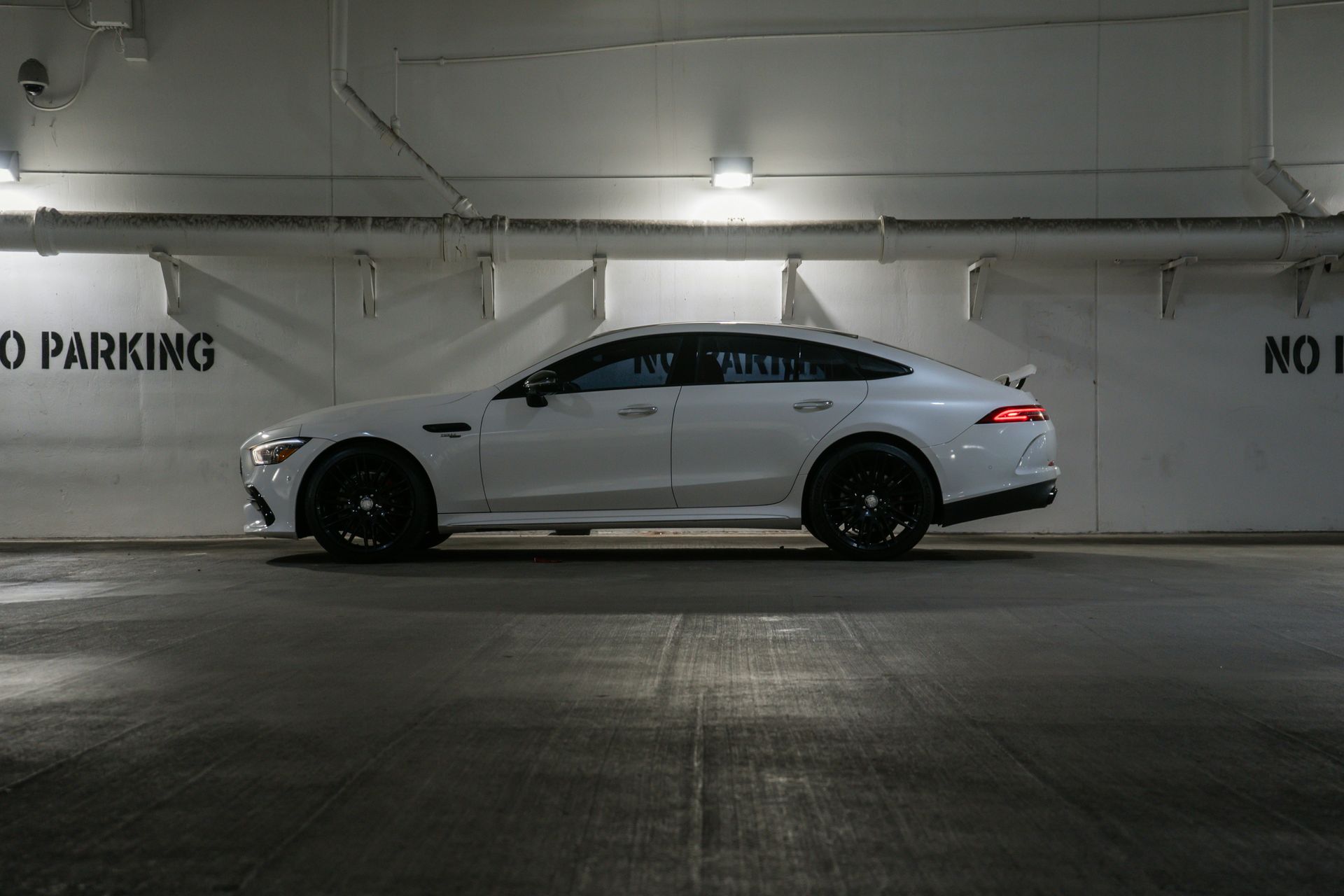 White Mercedes-AMG GT 4-door coupe parked in an underground parking garage.