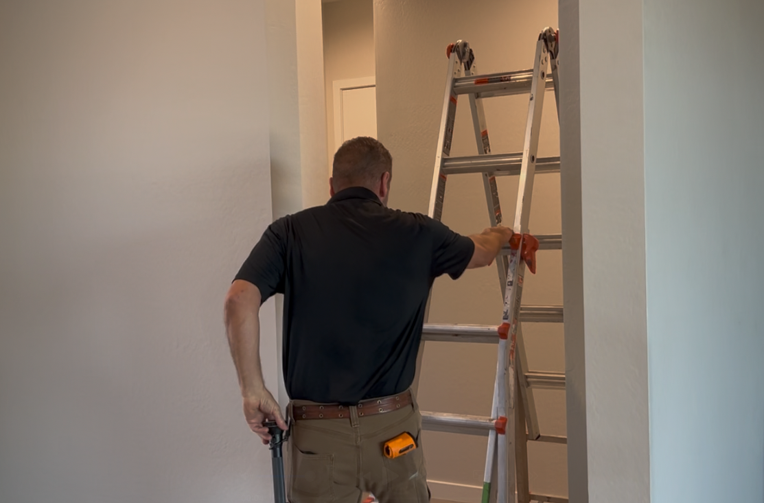 Real estate agent showing a couple a room with large windows, gesturing toward the view.