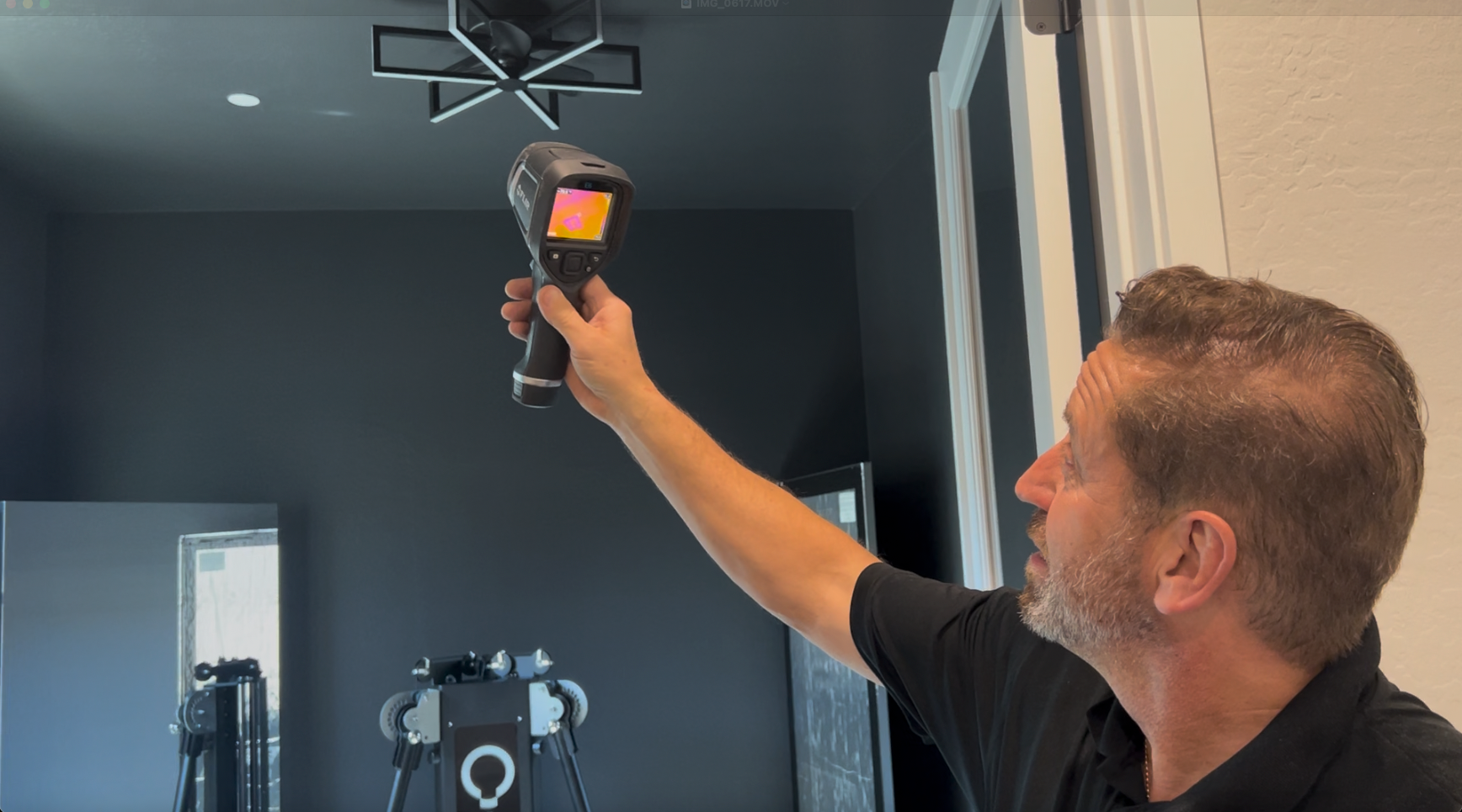 Man uses a thermal imaging camera on a ceiling, measuring heat in a room.