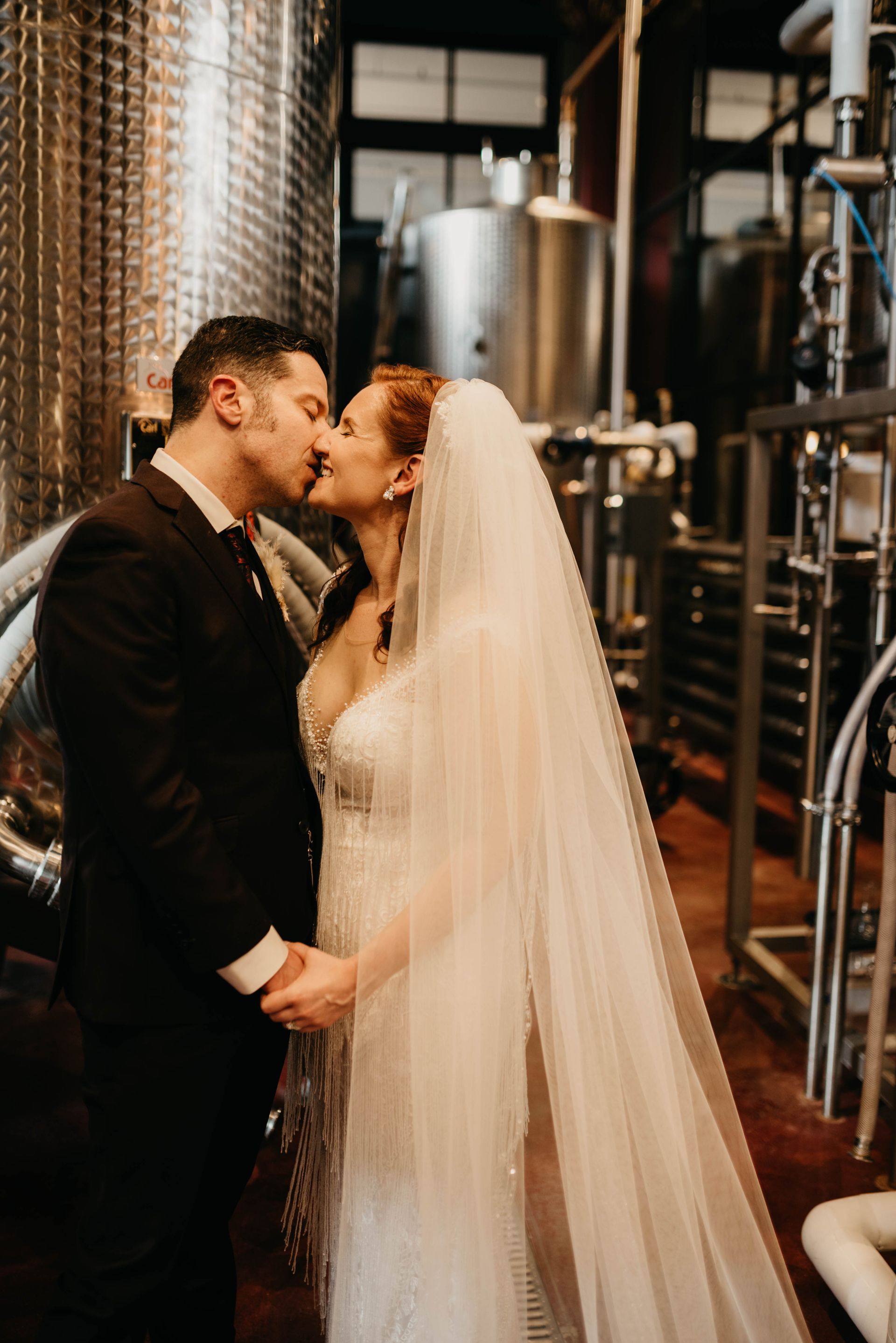 a bride and groom kissing in front of a large metal tank