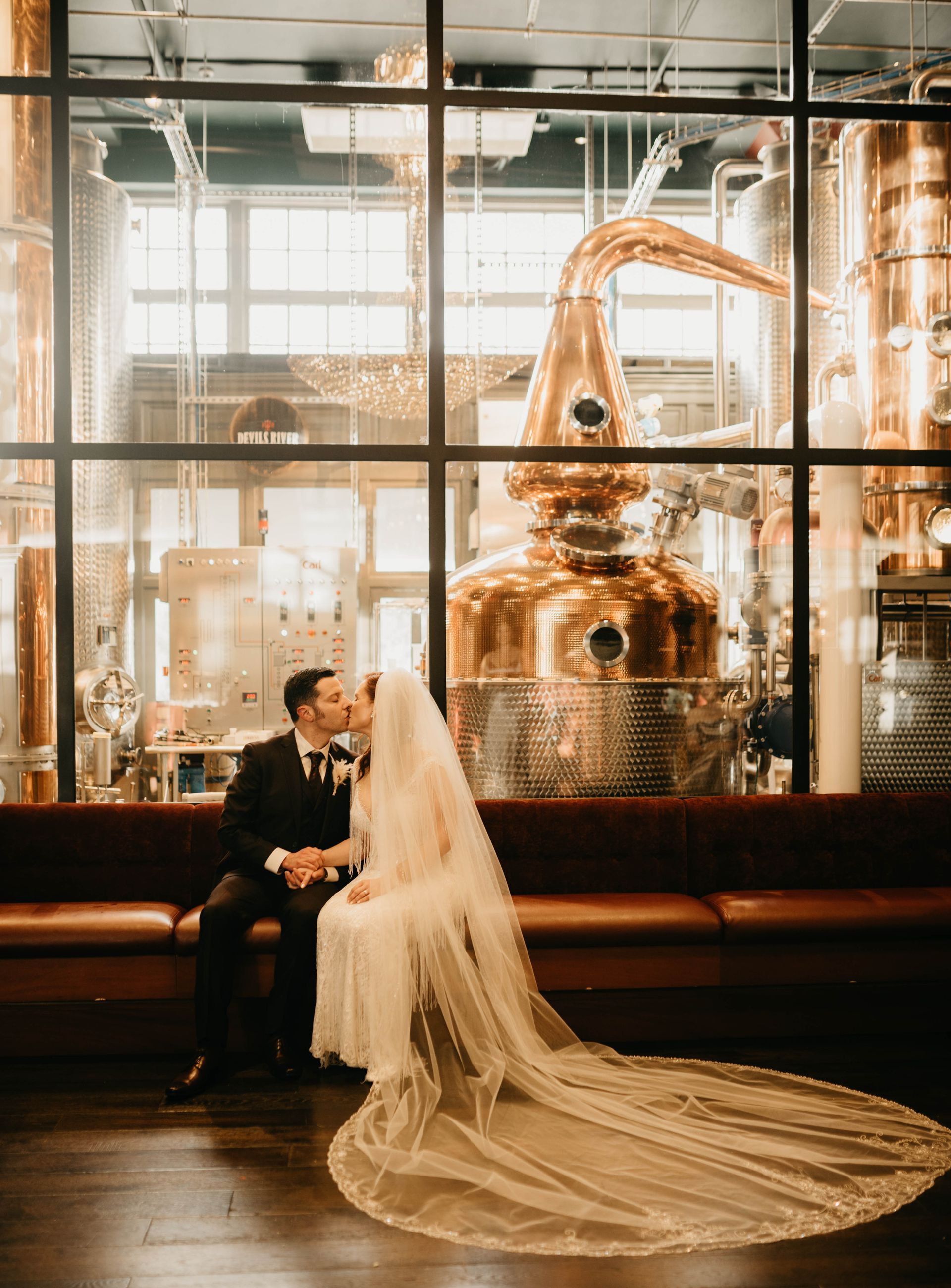 a bride and groom are kissing in front of a distillery