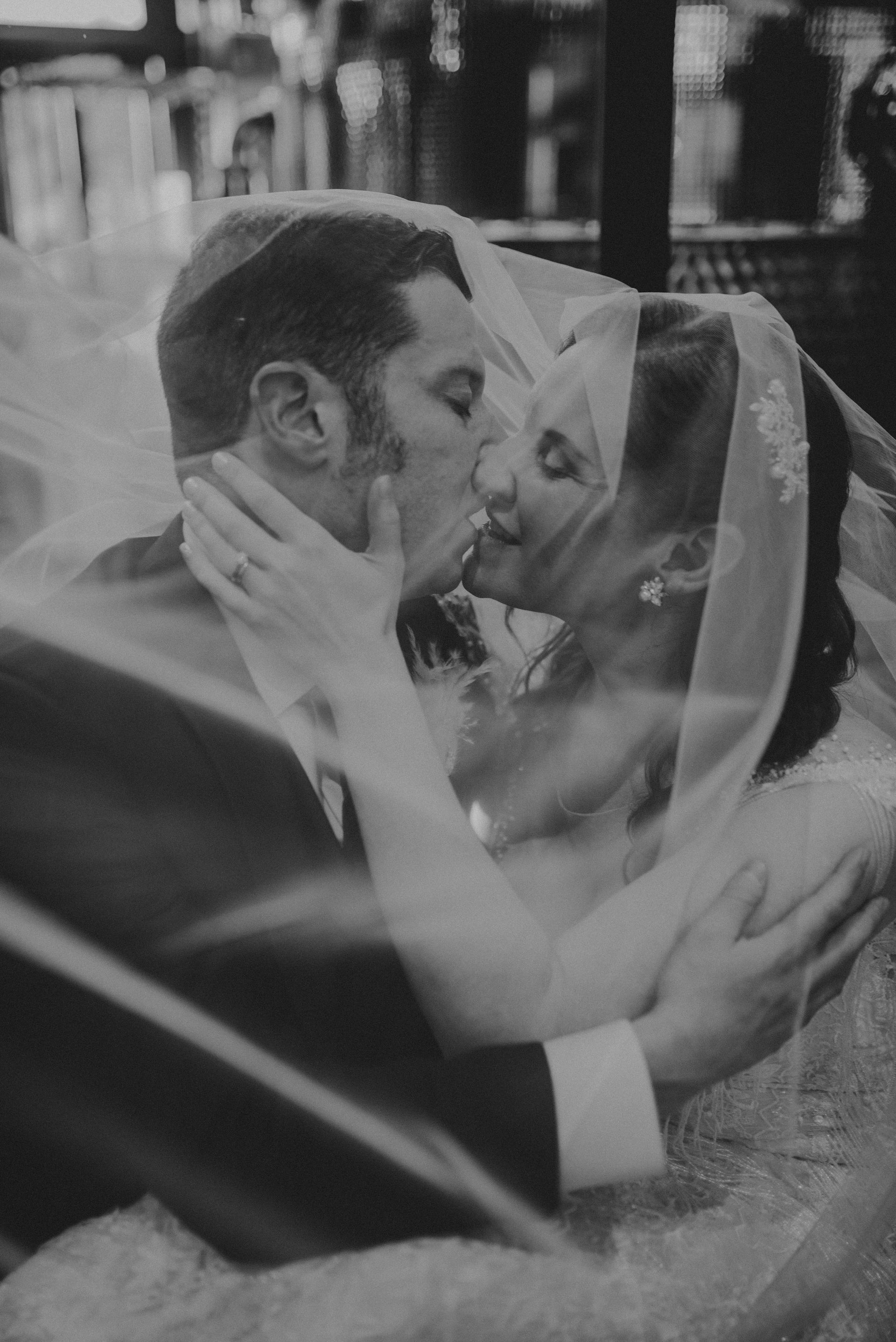 a bride and groom are kissing under a veil