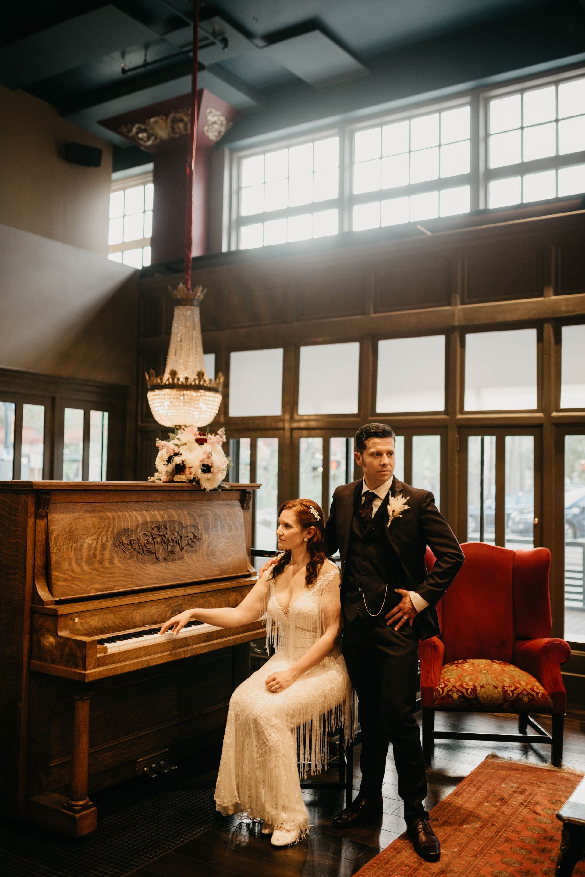 a bride and groom pose in front of an old piano