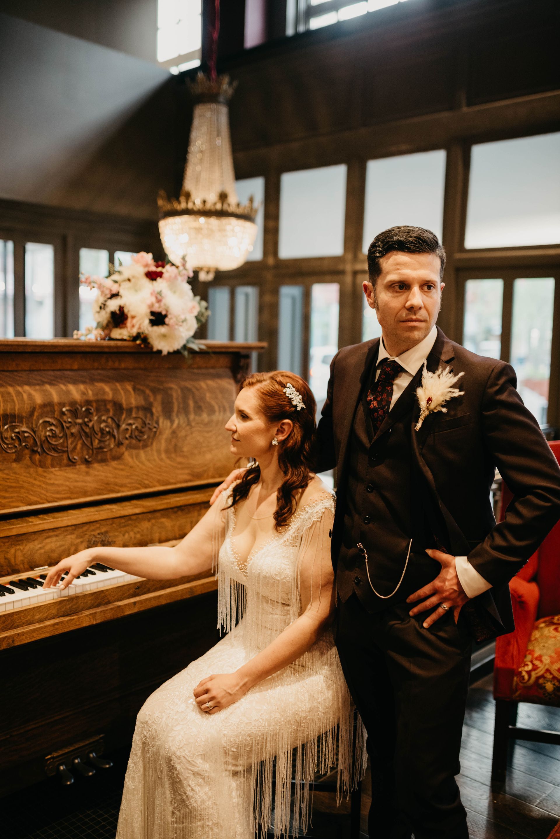 a bride and groom pose in front of a piano