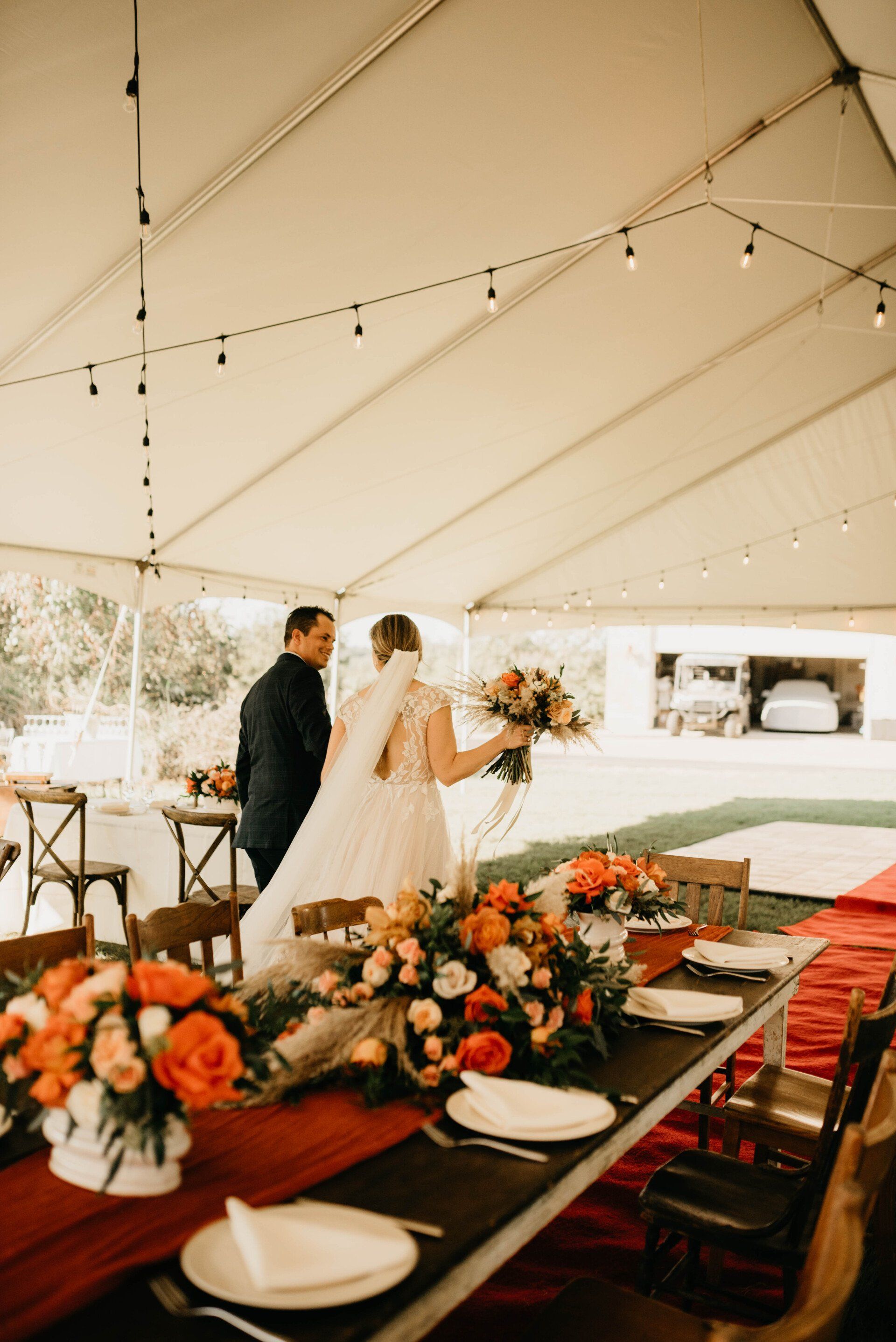 a bride and groom are walking under a tent