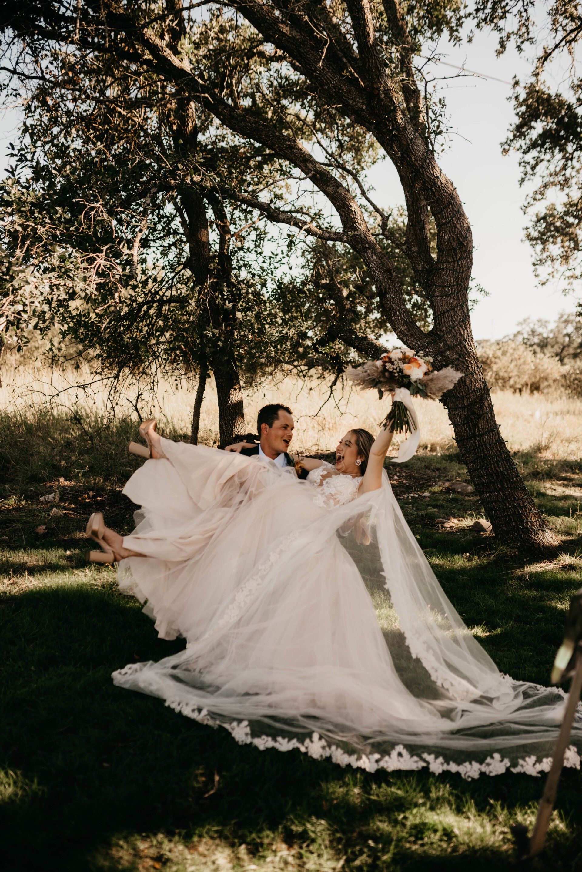 a bride and groom pose for a picture under a tree