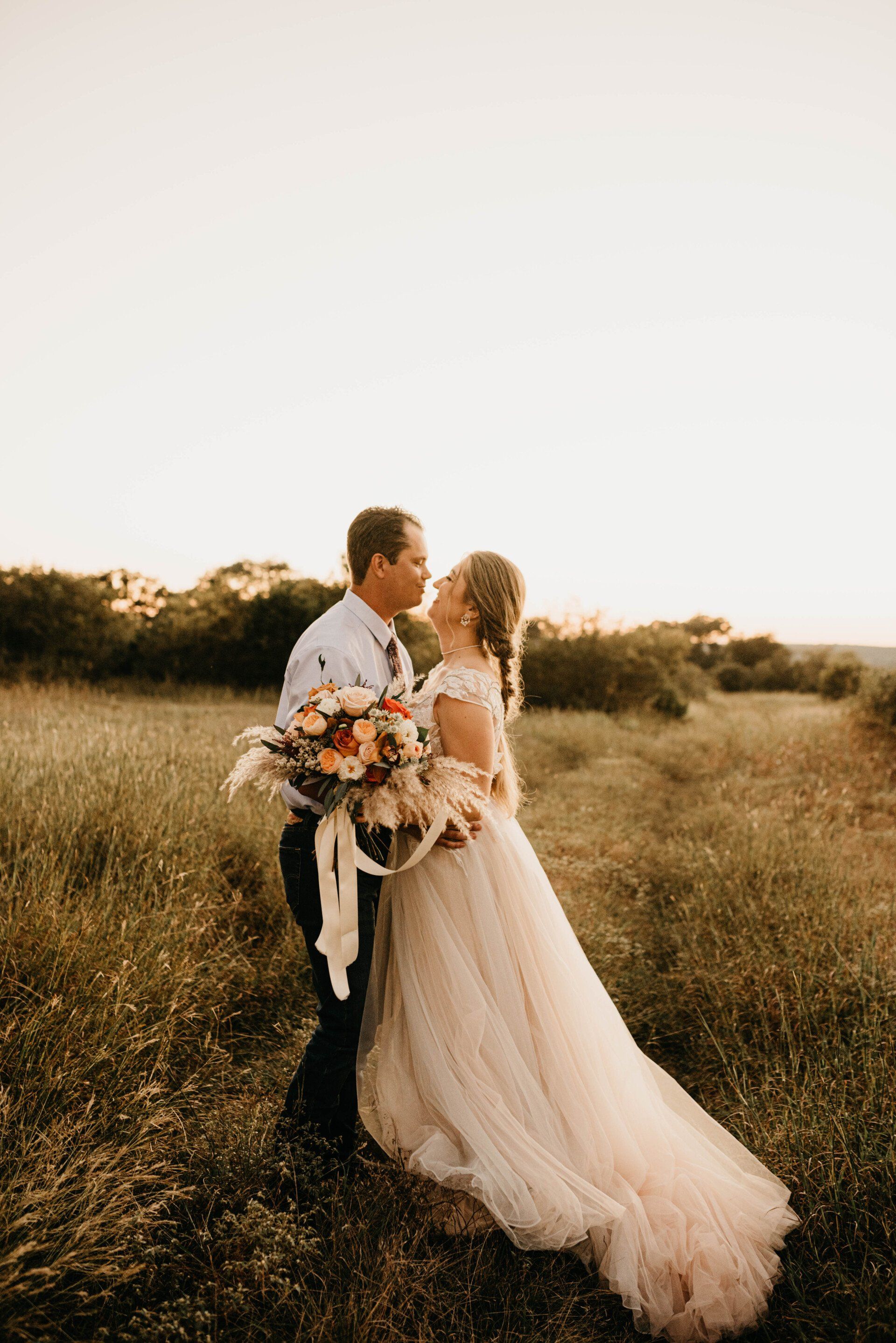 a bride and groom are kissing in a field