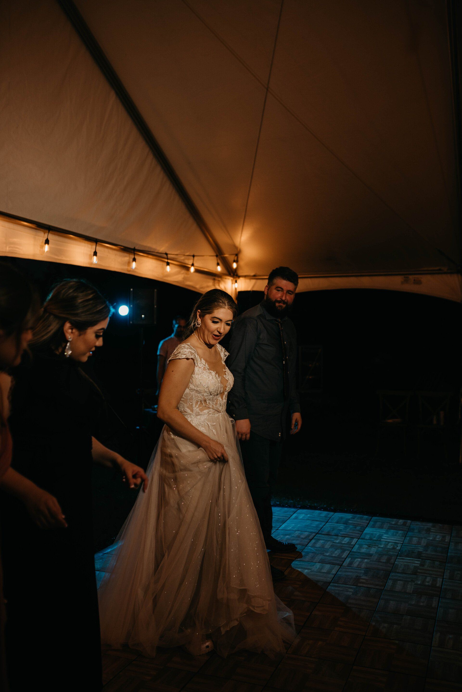 a woman in a wedding dress is dancing under a tent