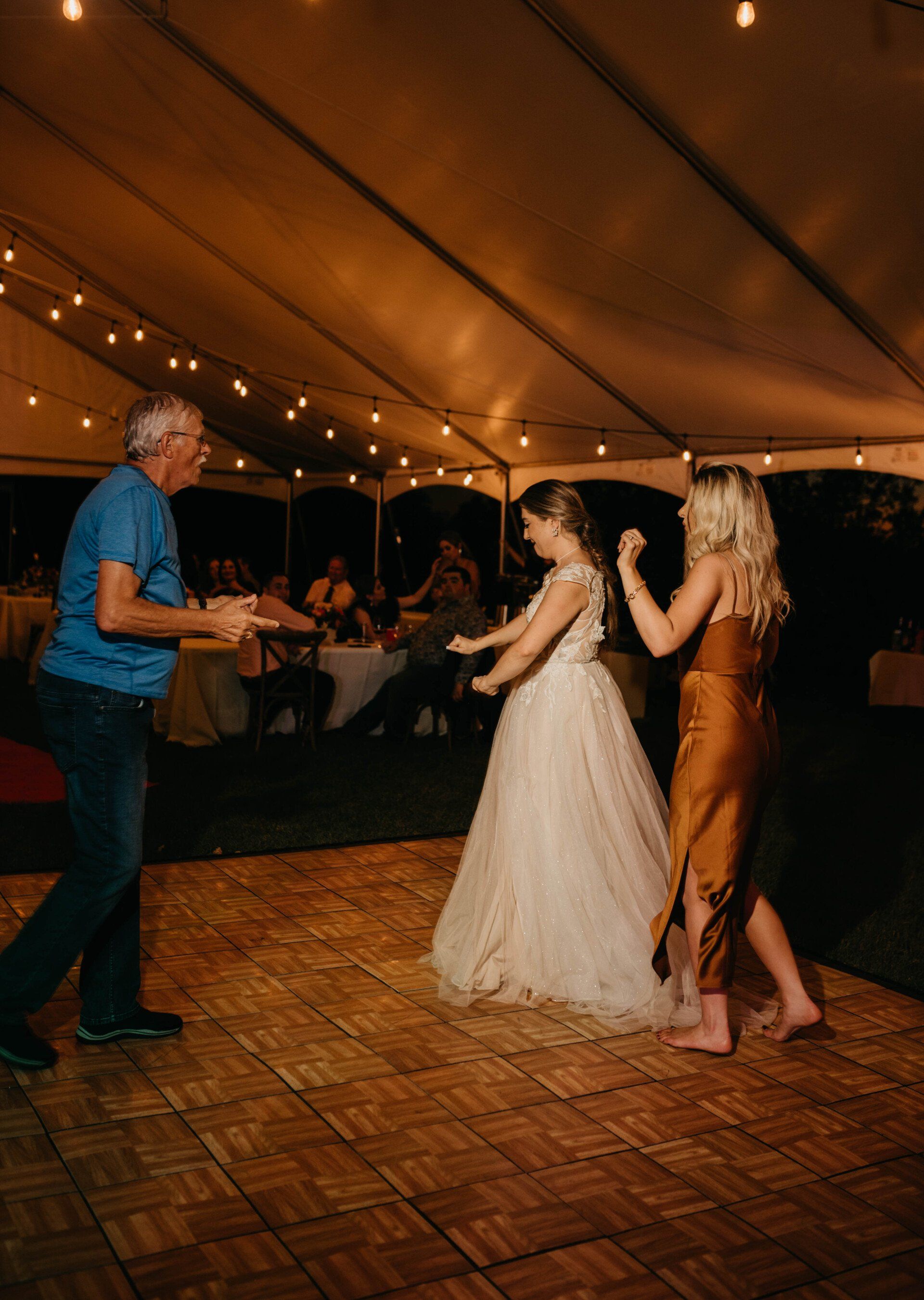a group of people are dancing under a tent