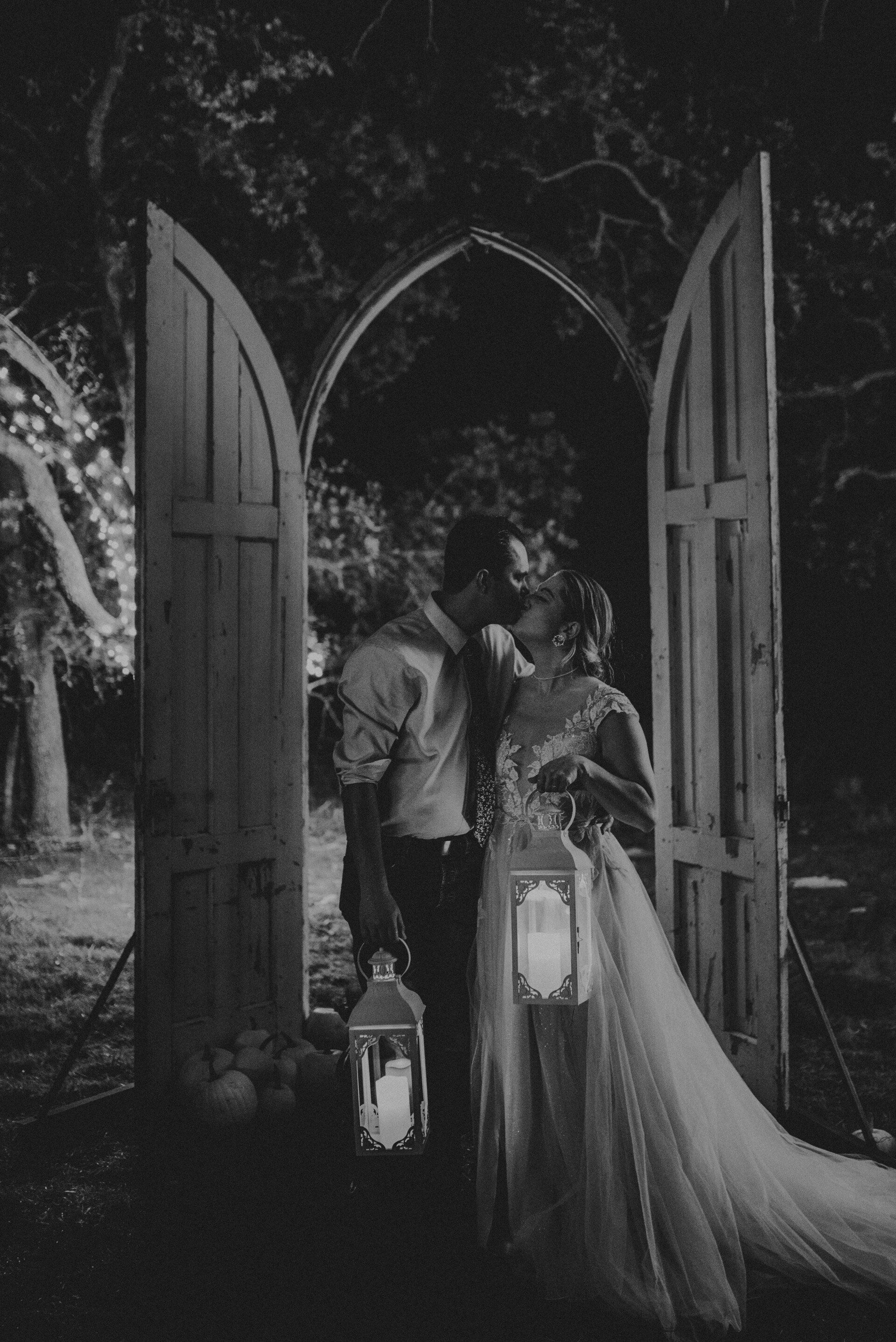 a black and white photo of a bride and groom holding lanterns