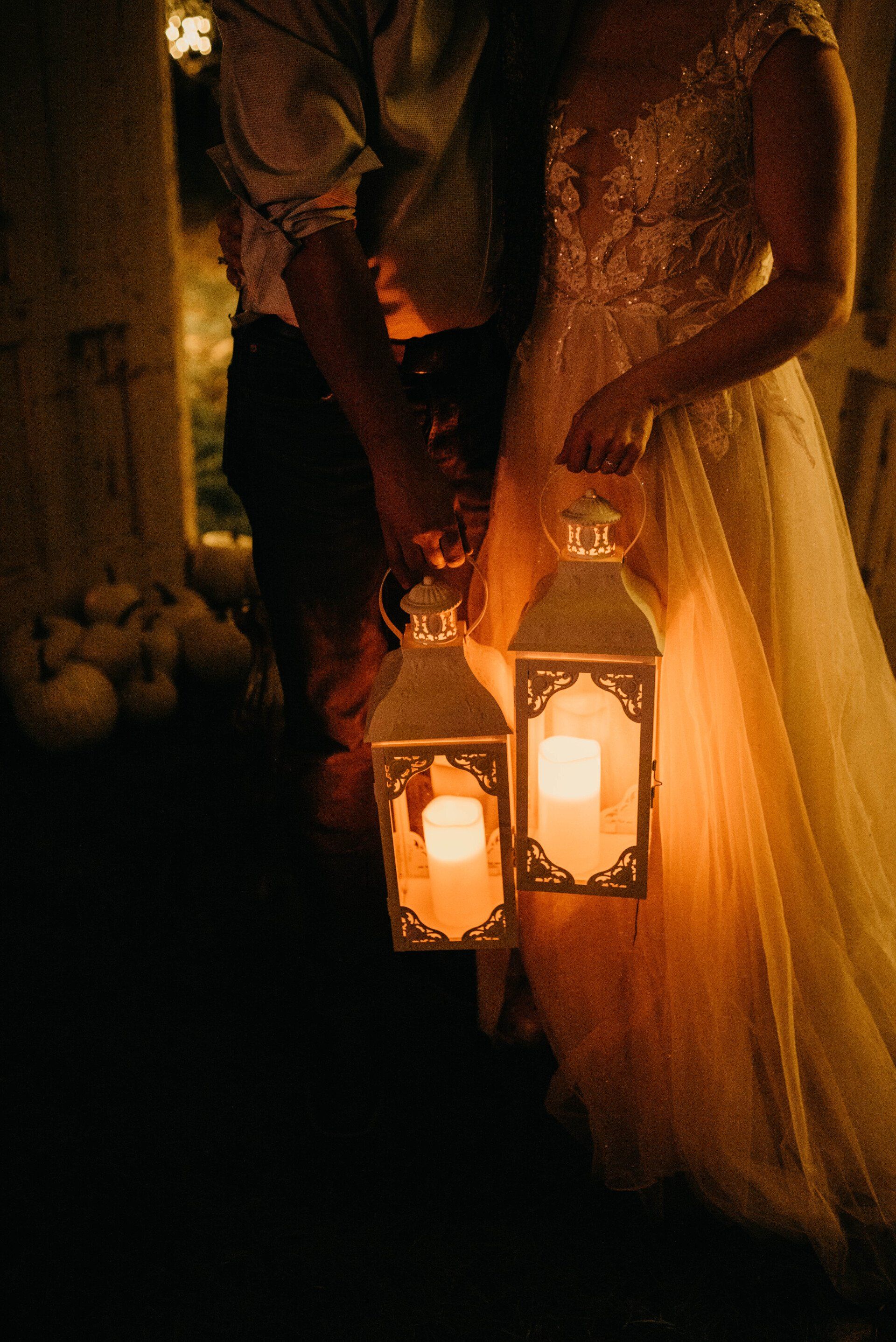 a bride and groom hold hands while holding lanterns with candles in them