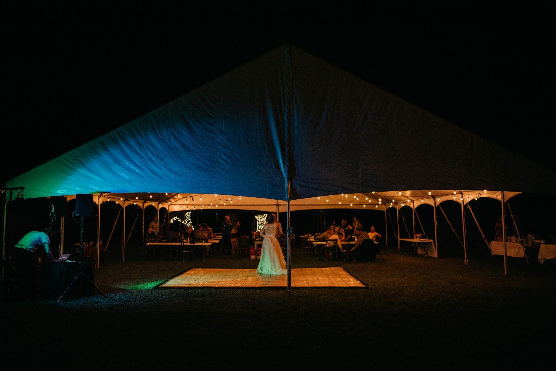 a bride and groom are dancing under a tent at night