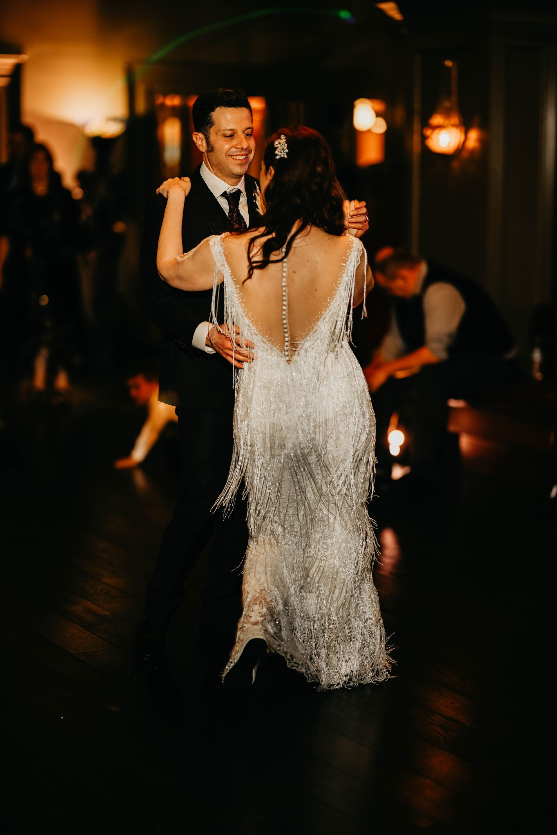 a bride and groom are dancing in a dark room